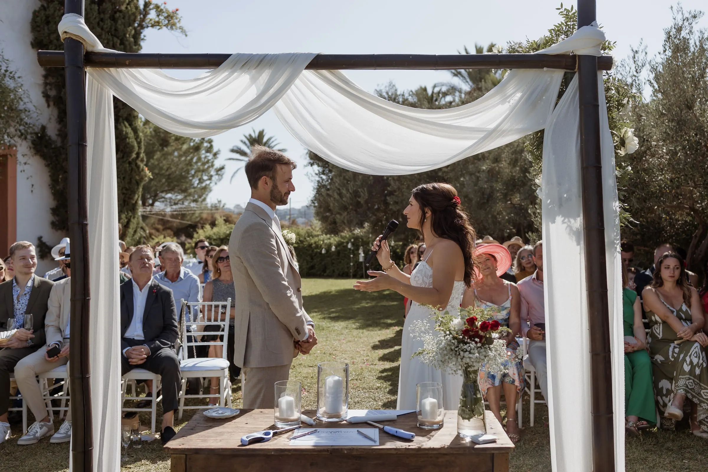 The bride reading her vows to the groom under a white draped canopy in the garden, Hacienda San José, Mijas