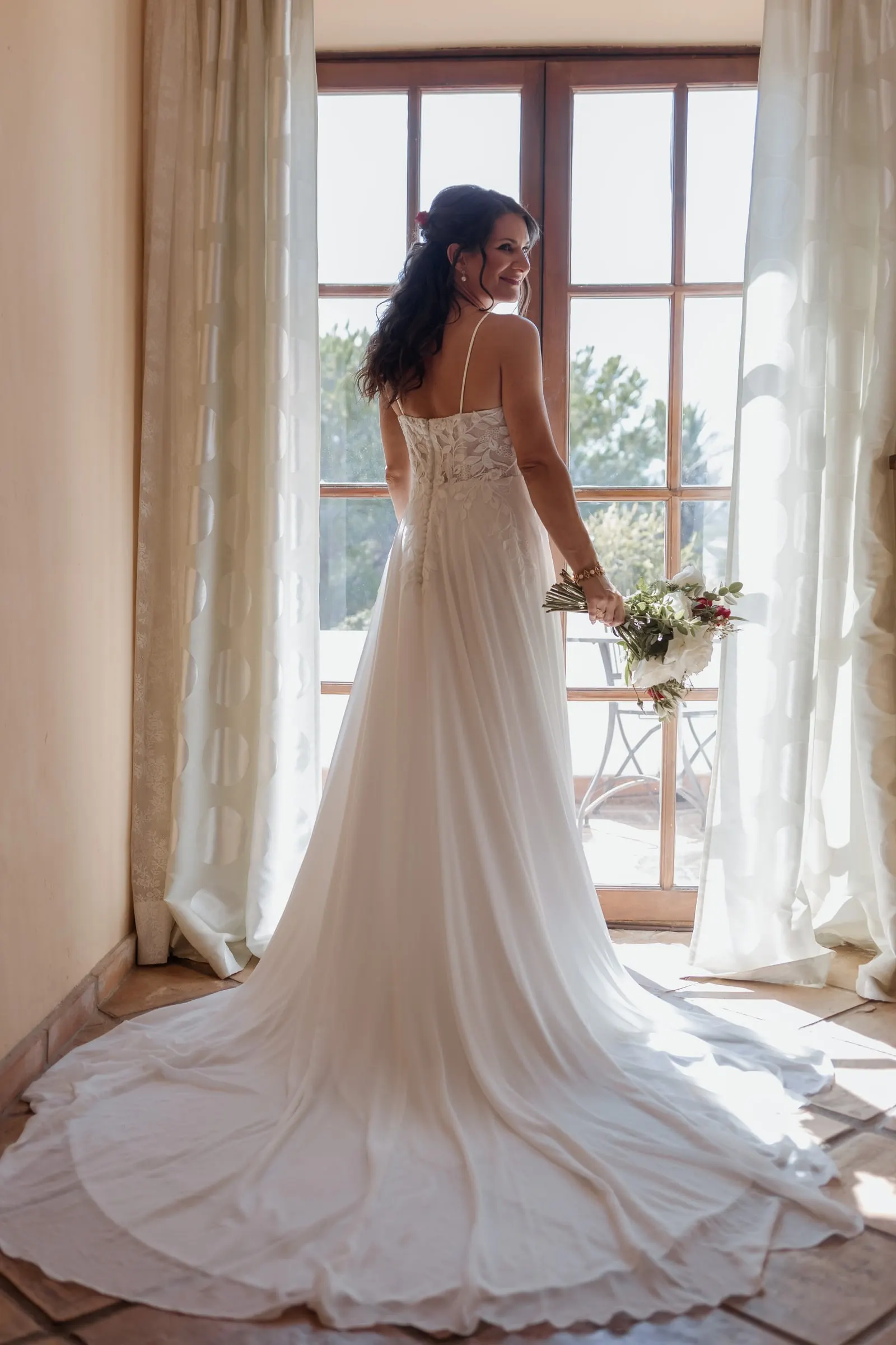 The bride seen from behind by an open window, her long train spread on the floor, Hacienda San José, Mijas