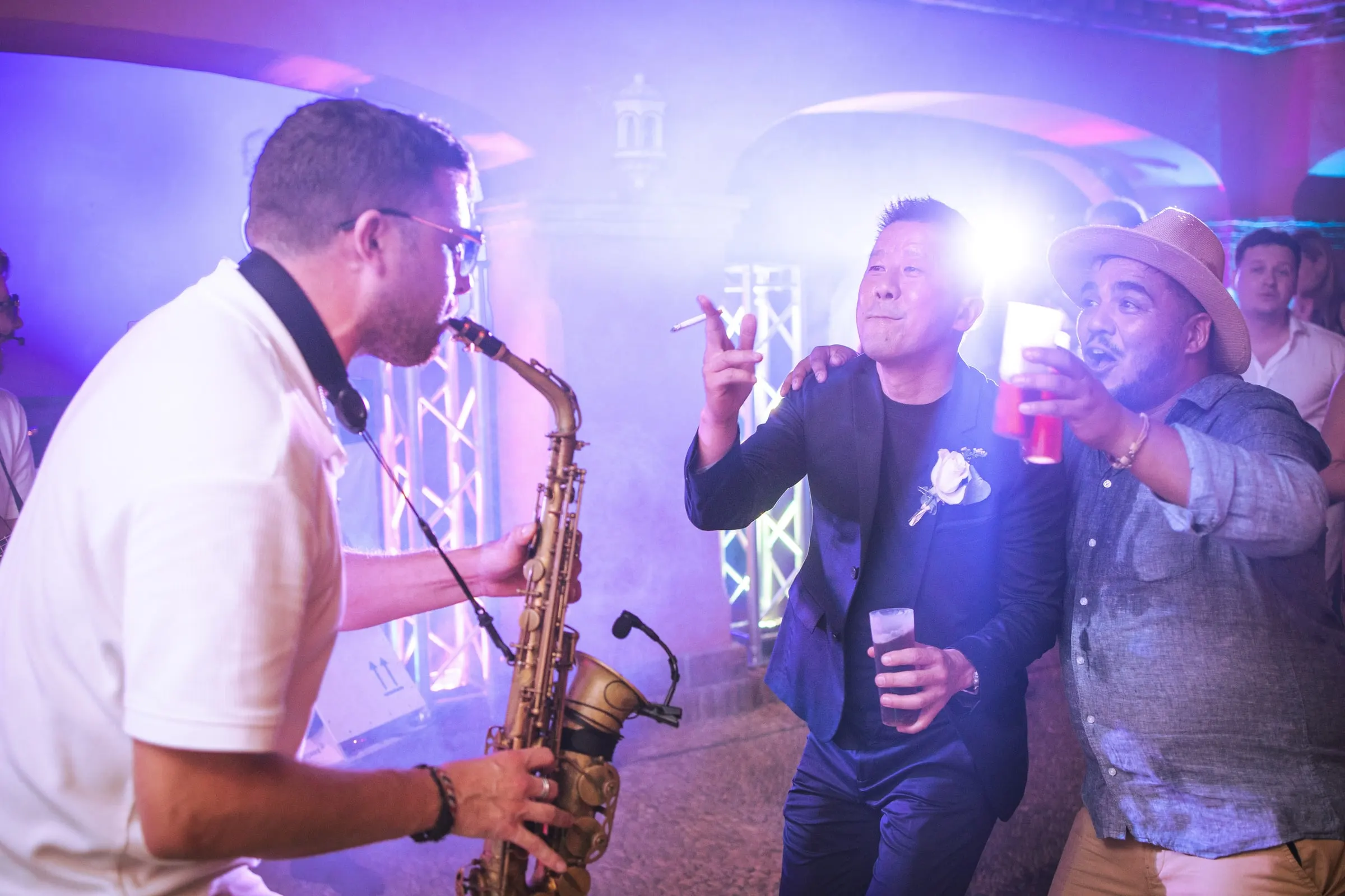 A saxophonist playing as guests dance in purple light during the party, Hacienda San José, Mijas