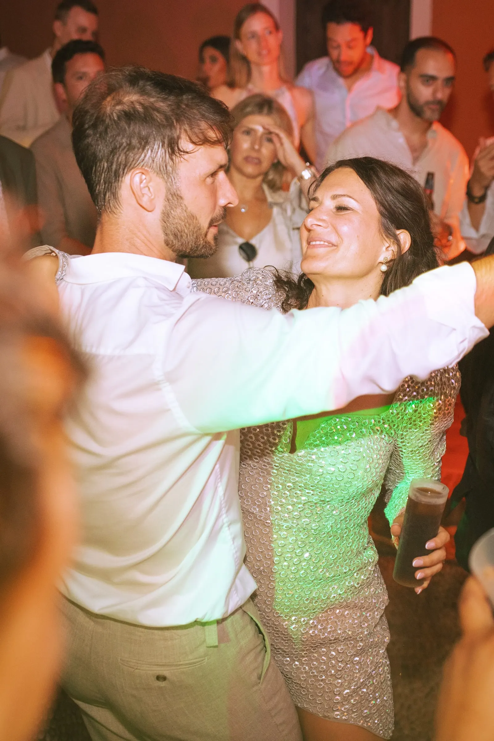 The groom and a guest in a sequinned dress dancing among the crowd at night, Hacienda San José, Mijas
