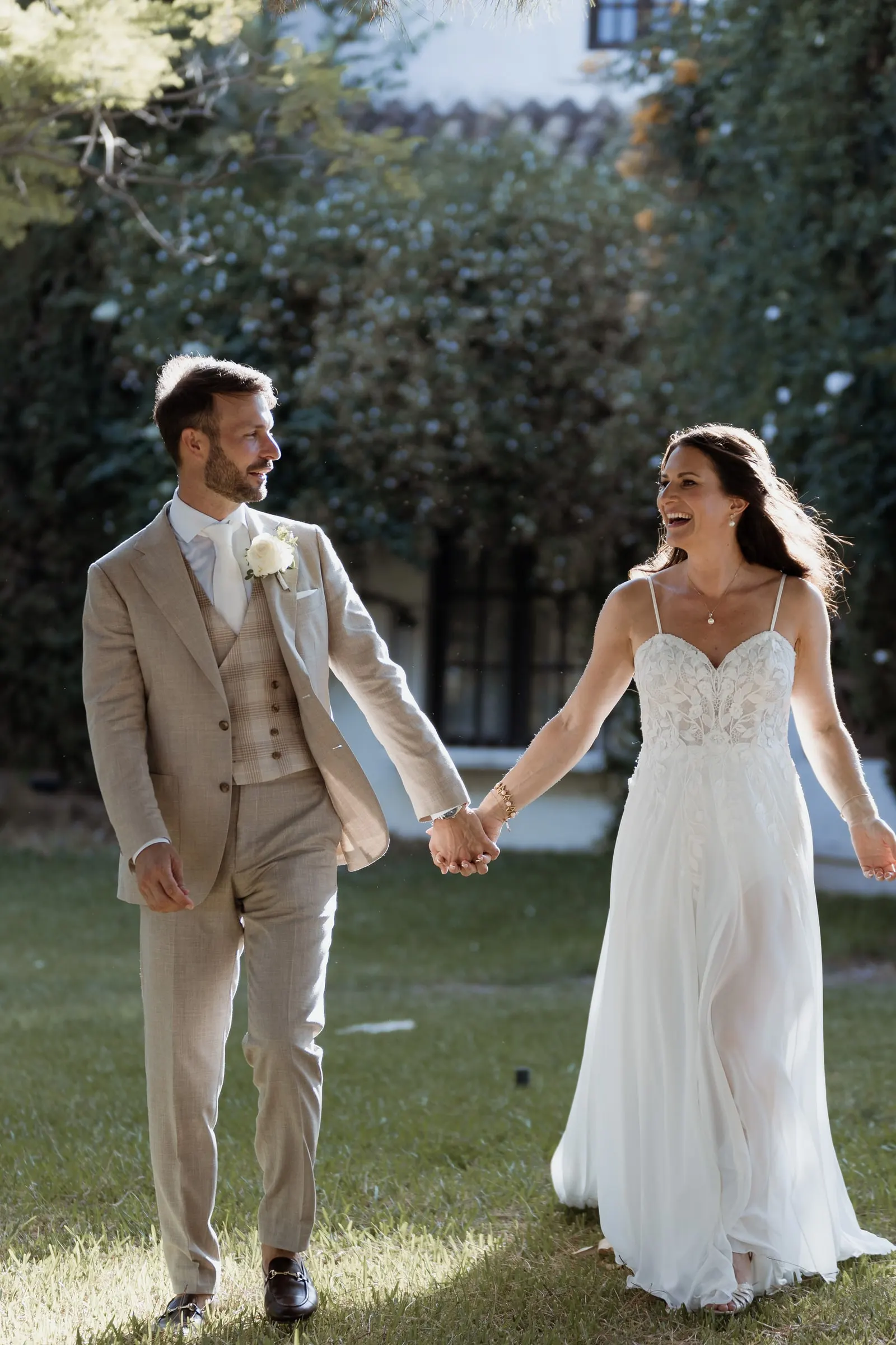 Bride and groom laughing as they walk hand in hand across the lawn, Hacienda San José, Mijas