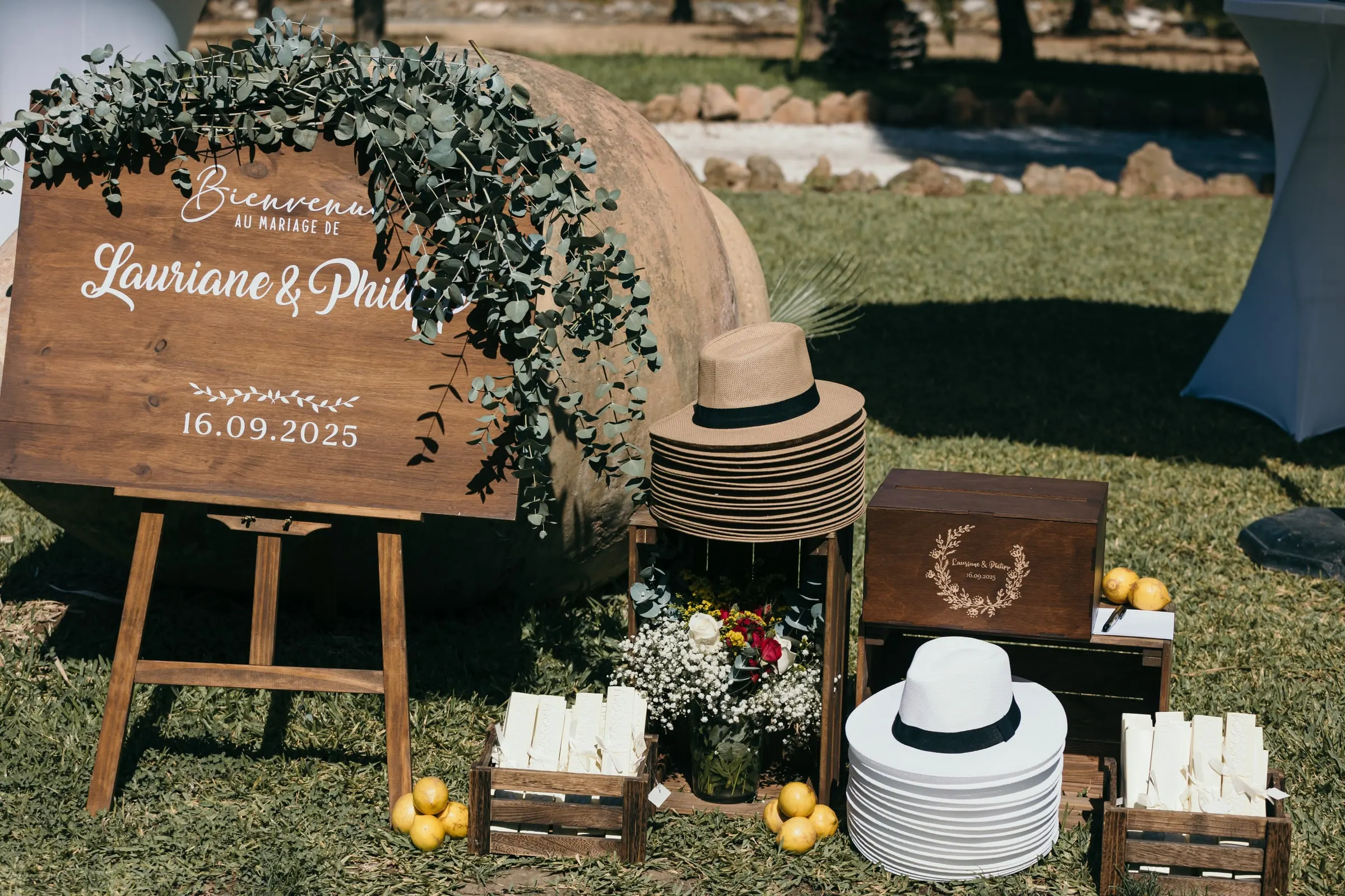 Wooden welcome sign with greenery beside straw hats and fans on the lawn, Hacienda San José, Mijas