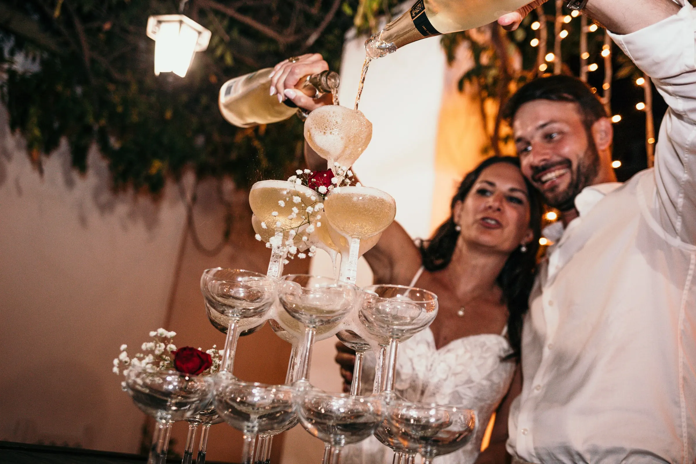 Bride and groom pouring champagne over a tower of coupes at night, Hacienda San José, Mijas