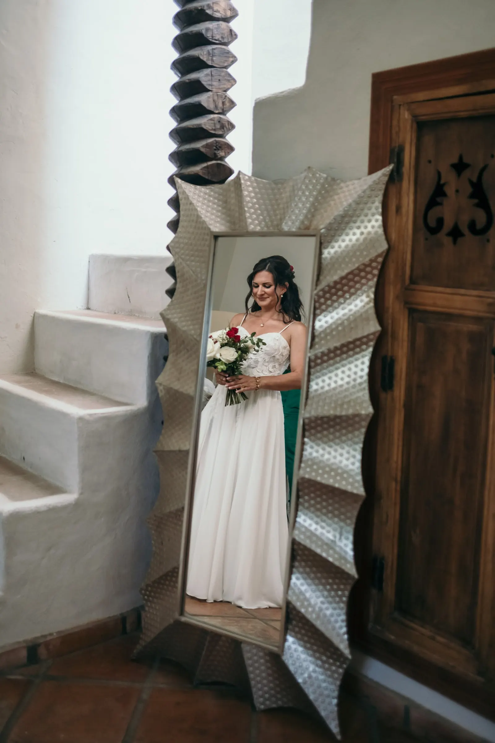 The bride reflected in a tall silver mirror beside a carved wooden door, Hacienda San José, Mijas