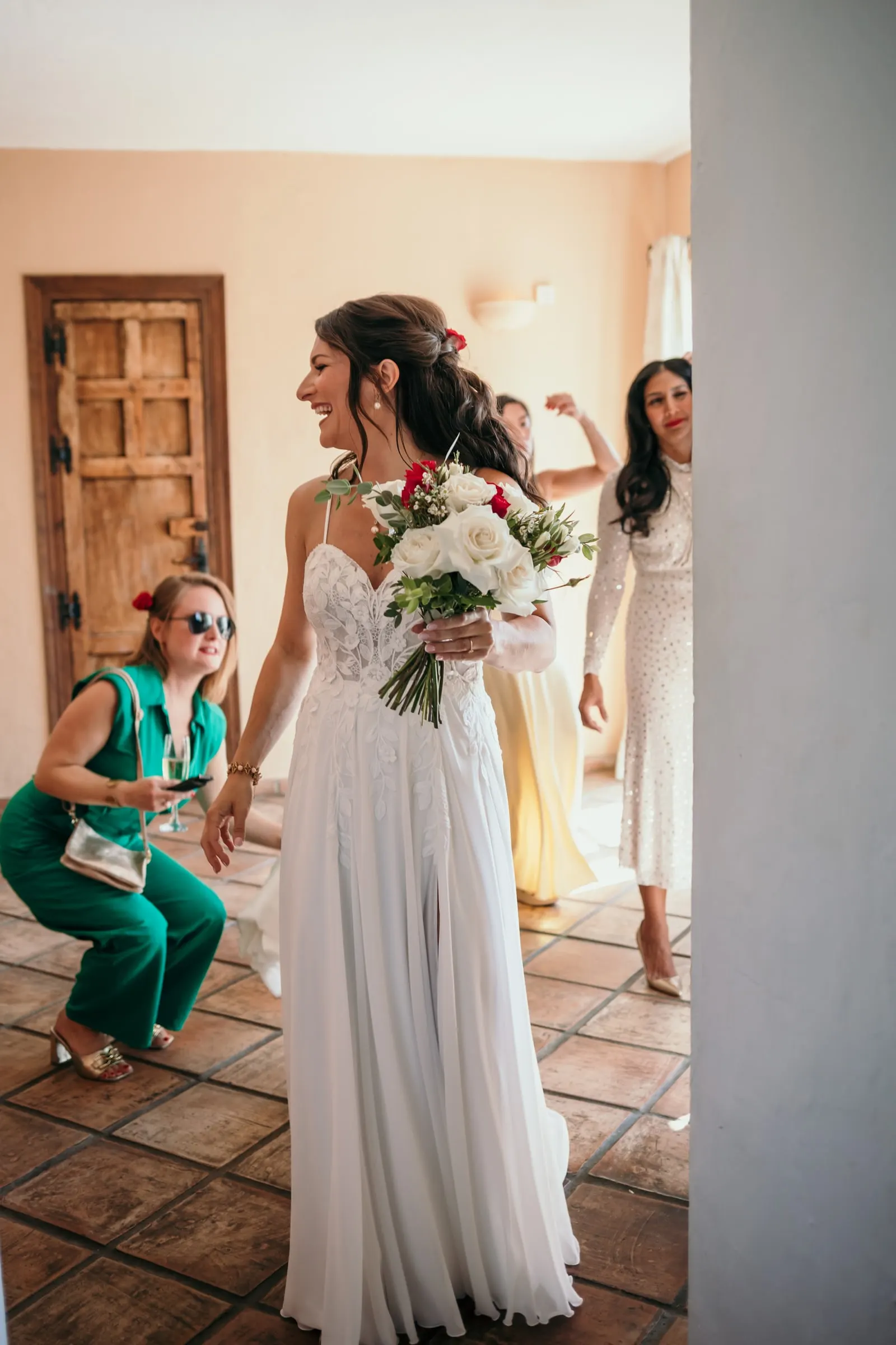 The bride smiling with her bouquet as excited friends crouch beside her, Hacienda San José, Mijas