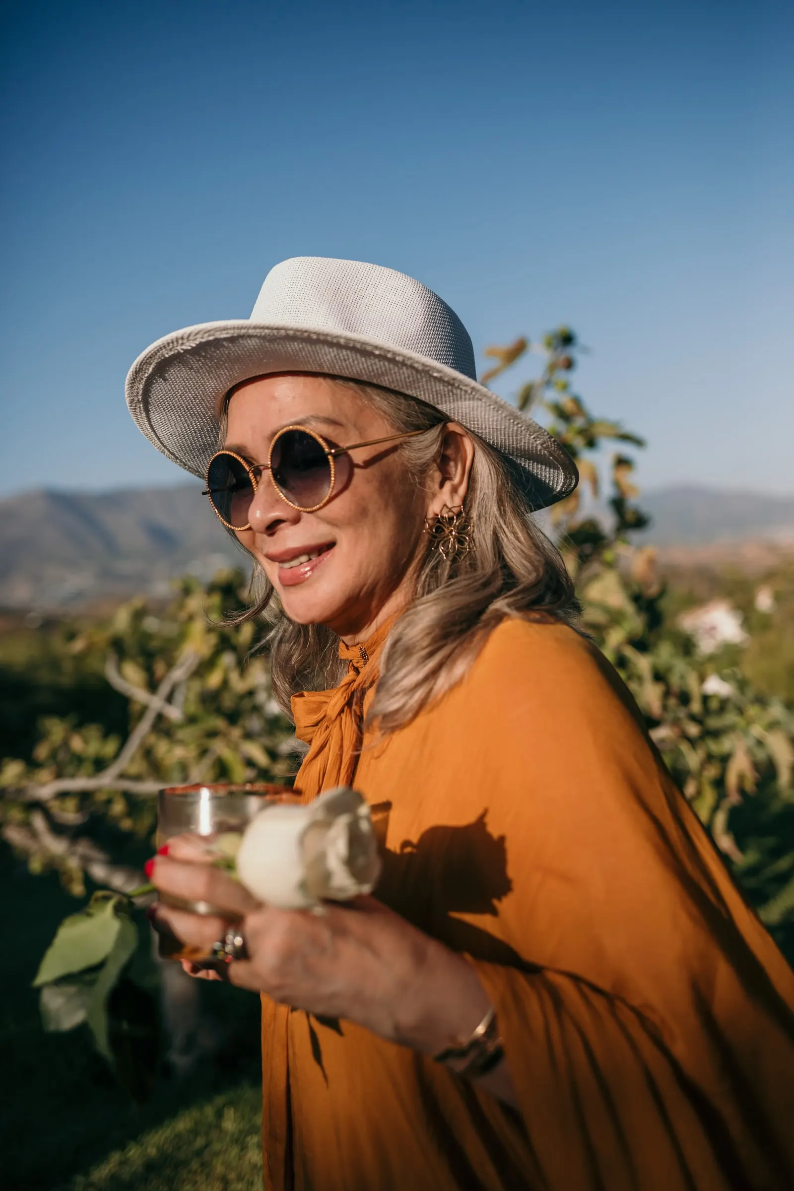 A guest in a felt hat and round sunglasses holding a drink in the sun, Hacienda San José, Mijas