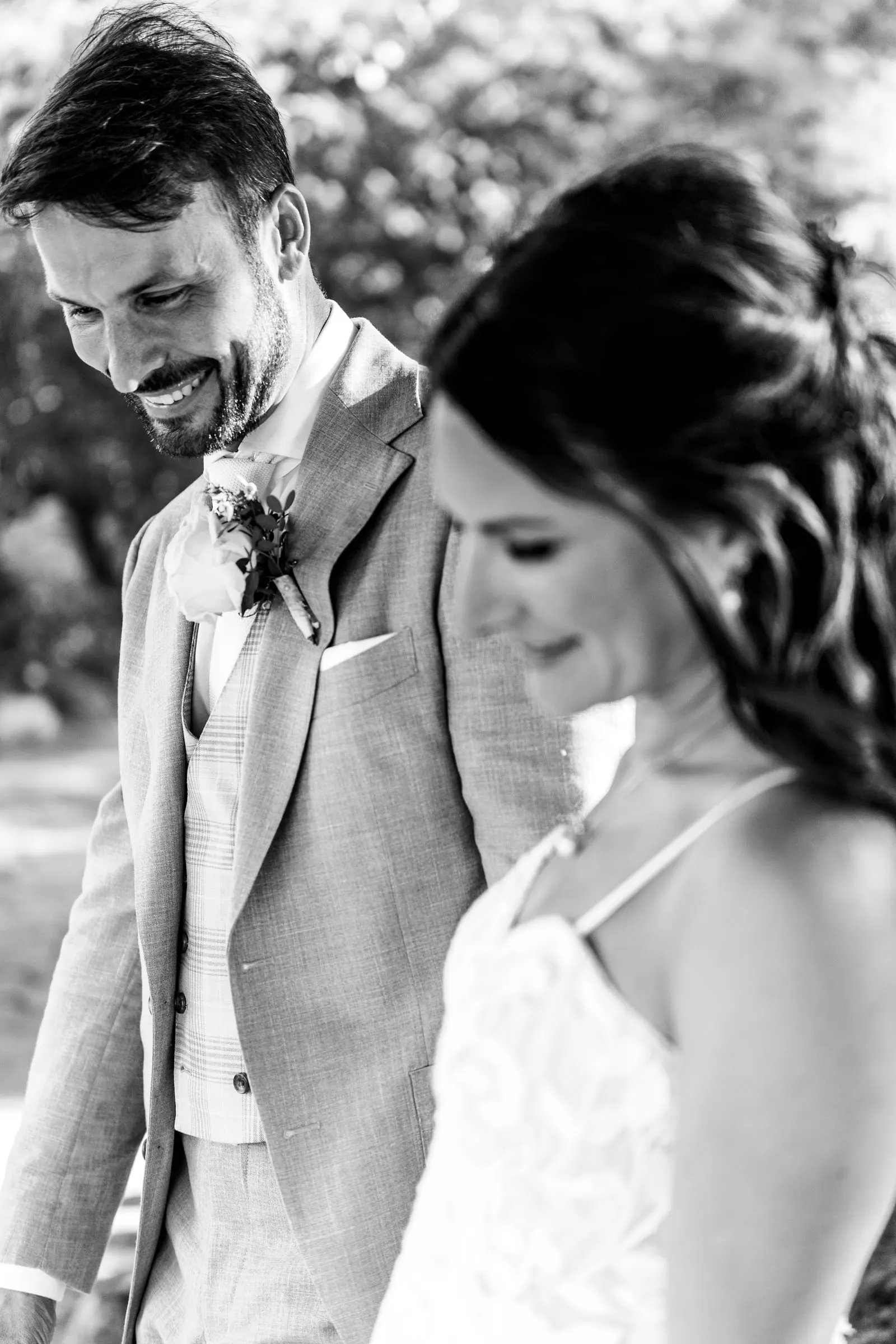 Black and white close-up of the couple smiling down, the groom's buttonhole in view, Hacienda San José, Mijas