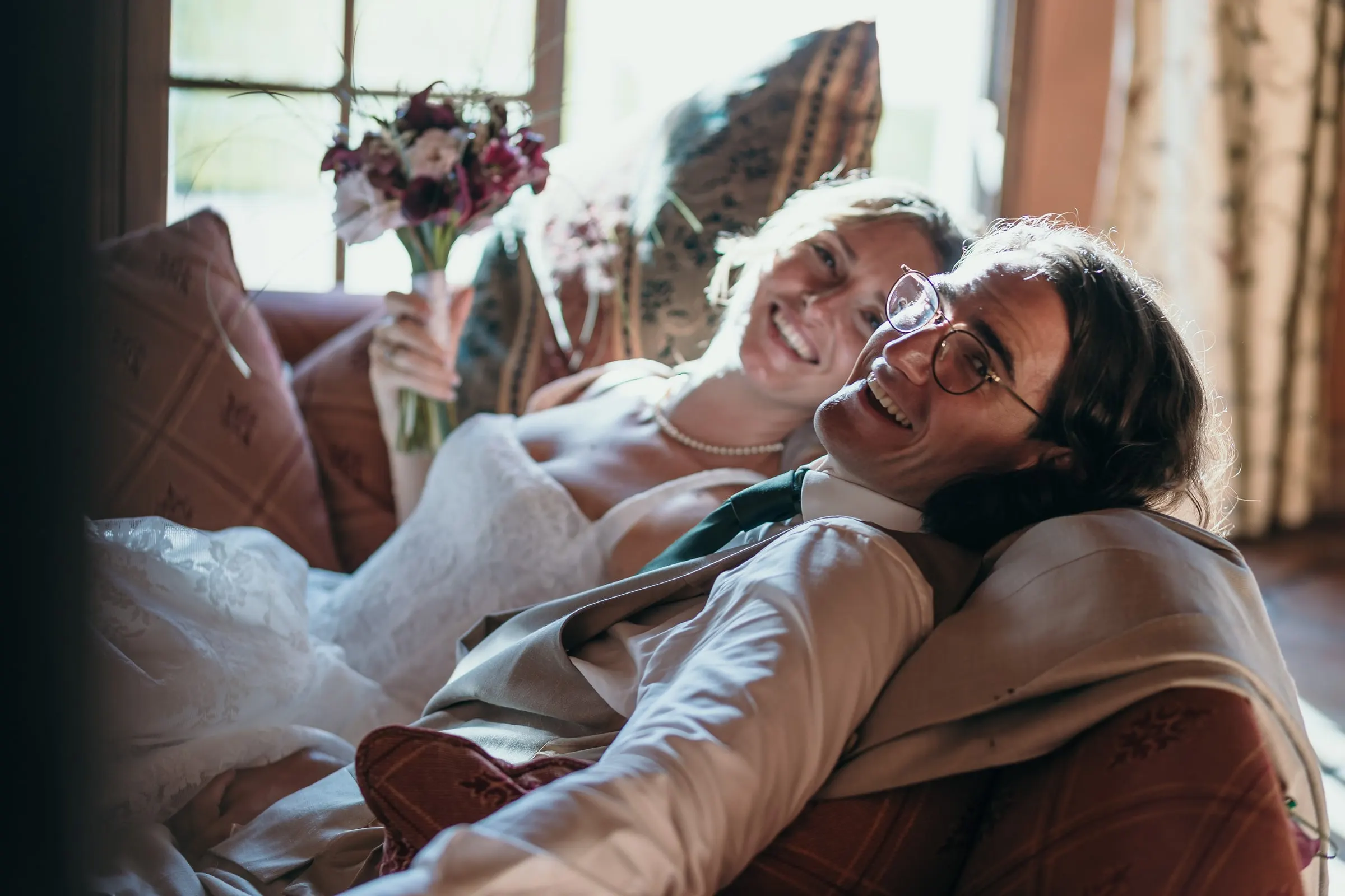 Bride and groom laughing as they lounge together on a sofa after the ceremony, Hacienda San José, Mijas