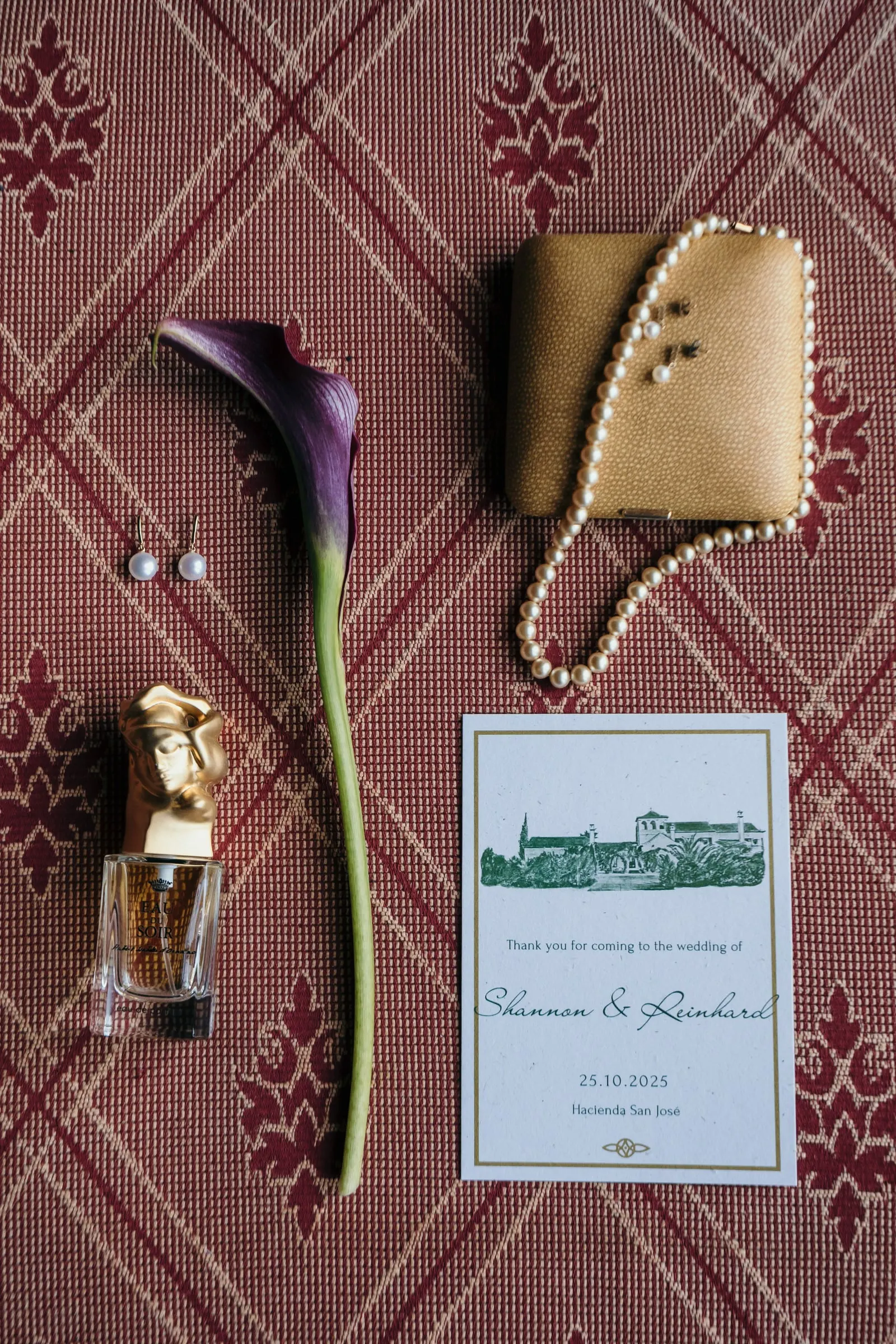 Flat lay of the wedding stationery, a calla lily, pearls and a perfume bottle, Hacienda San José, Mijas