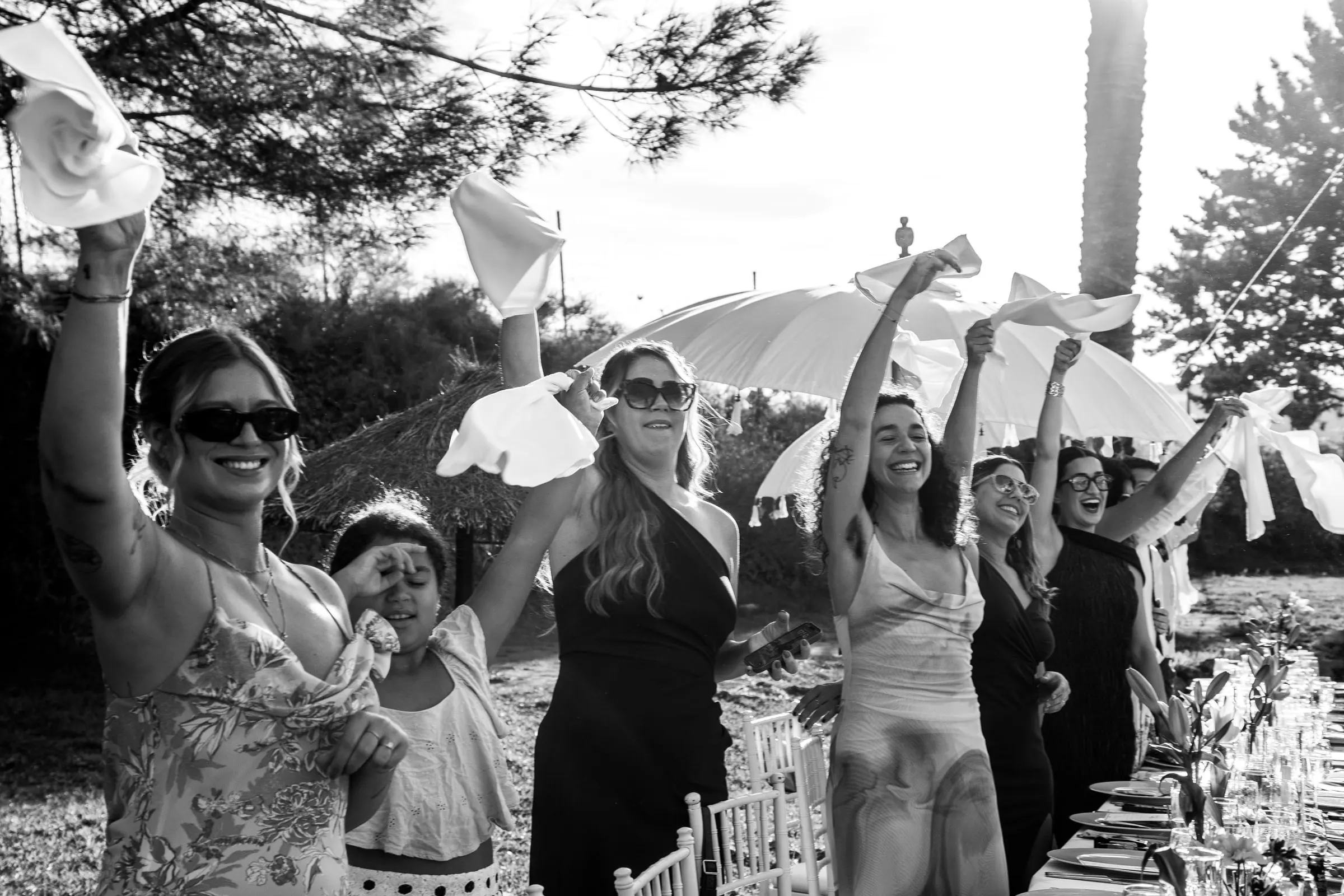 Black and white of guests cheering and waving napkins at the dinner table, Hacienda San José, Mijas