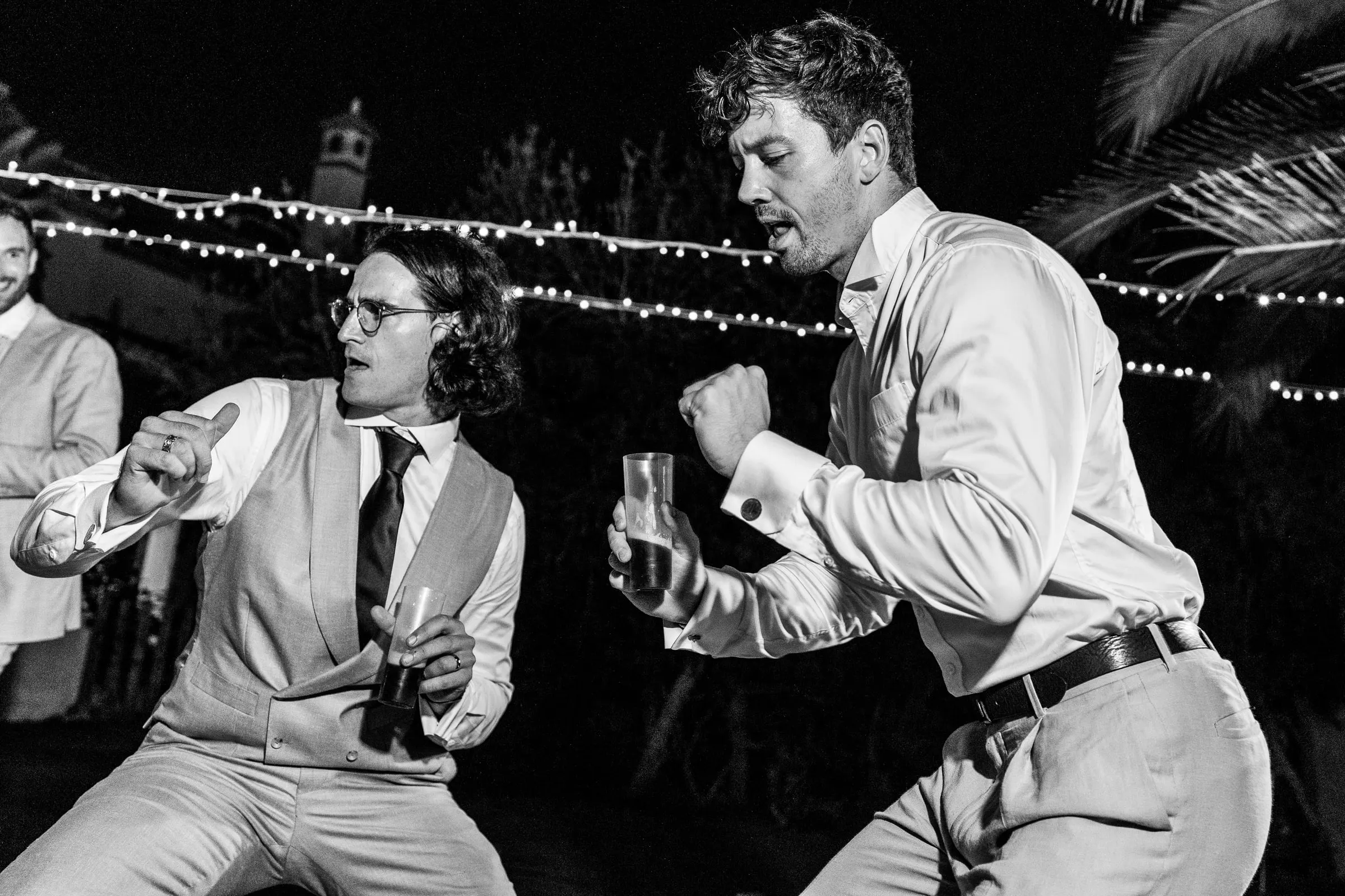 Black and white of the groom dancing energetically with a guest at the party at Hacienda San José, Mijas