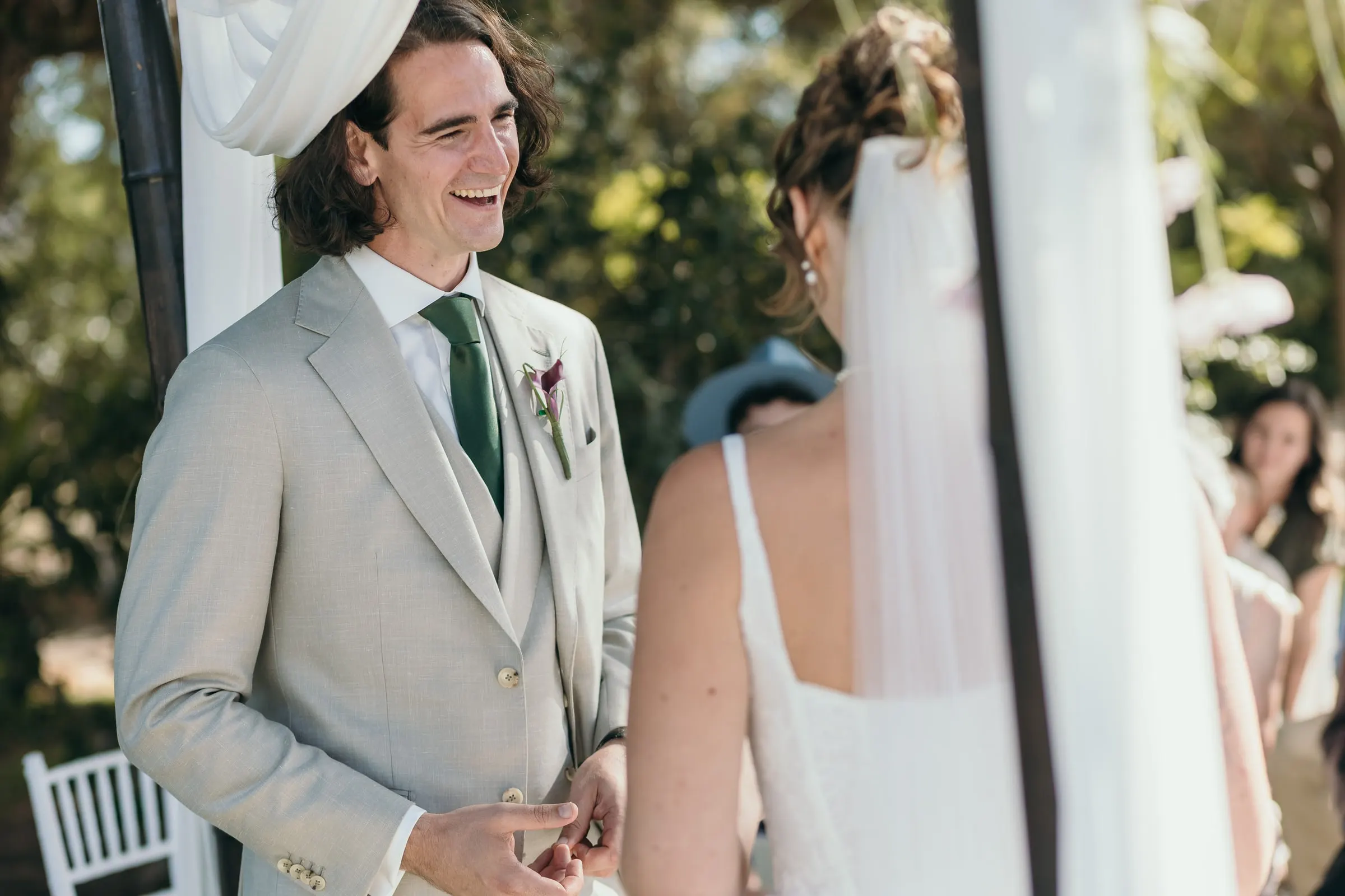 The groom smiling as he slides the ring onto the bride's finger at the ceremony, Hacienda San José, Mijas