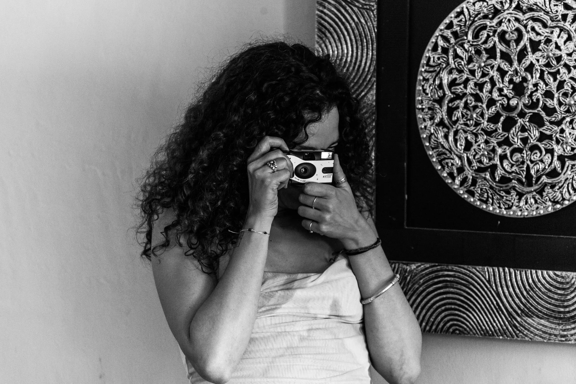 Black and white of a curly-haired guest taking a picture with a disposable camera, Hacienda San José, Mijas