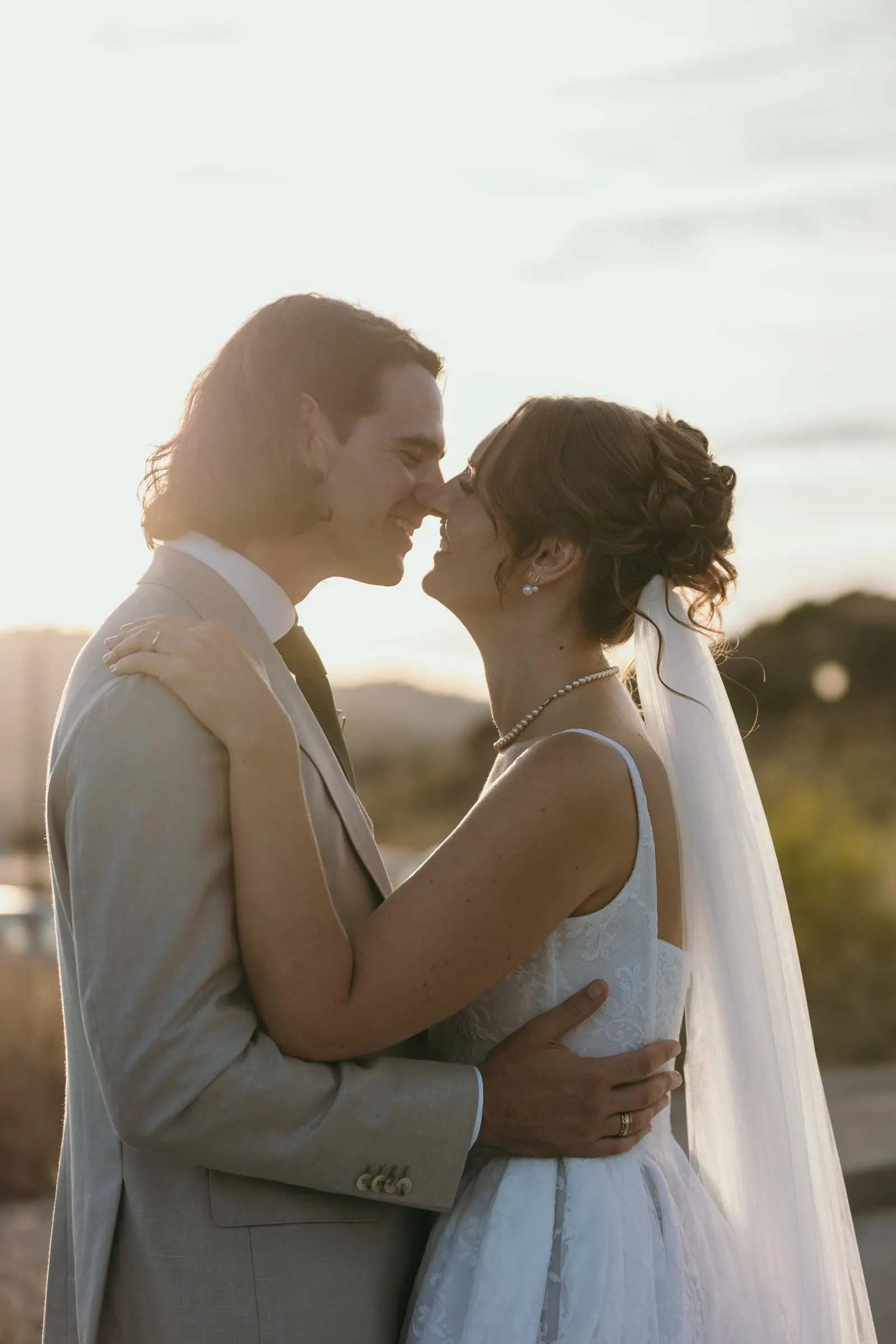 Bride and groom about to kiss in warm evening light, her veil glowing, Hacienda San José, Mijas
