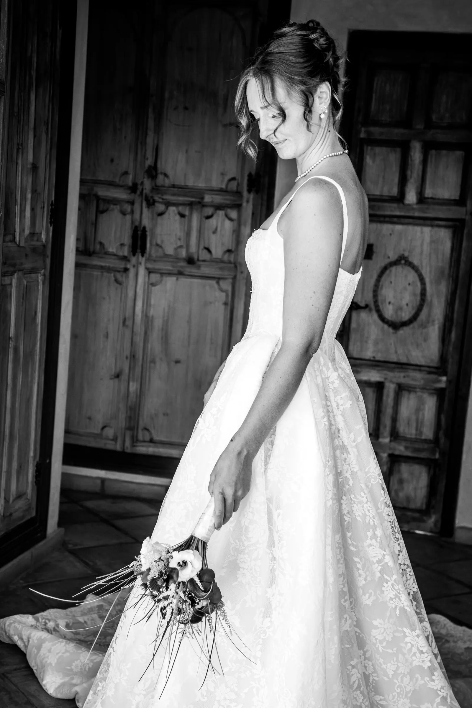 Black and white of the bride looking down at her bouquet by a wooden door, Hacienda San José, Mijas