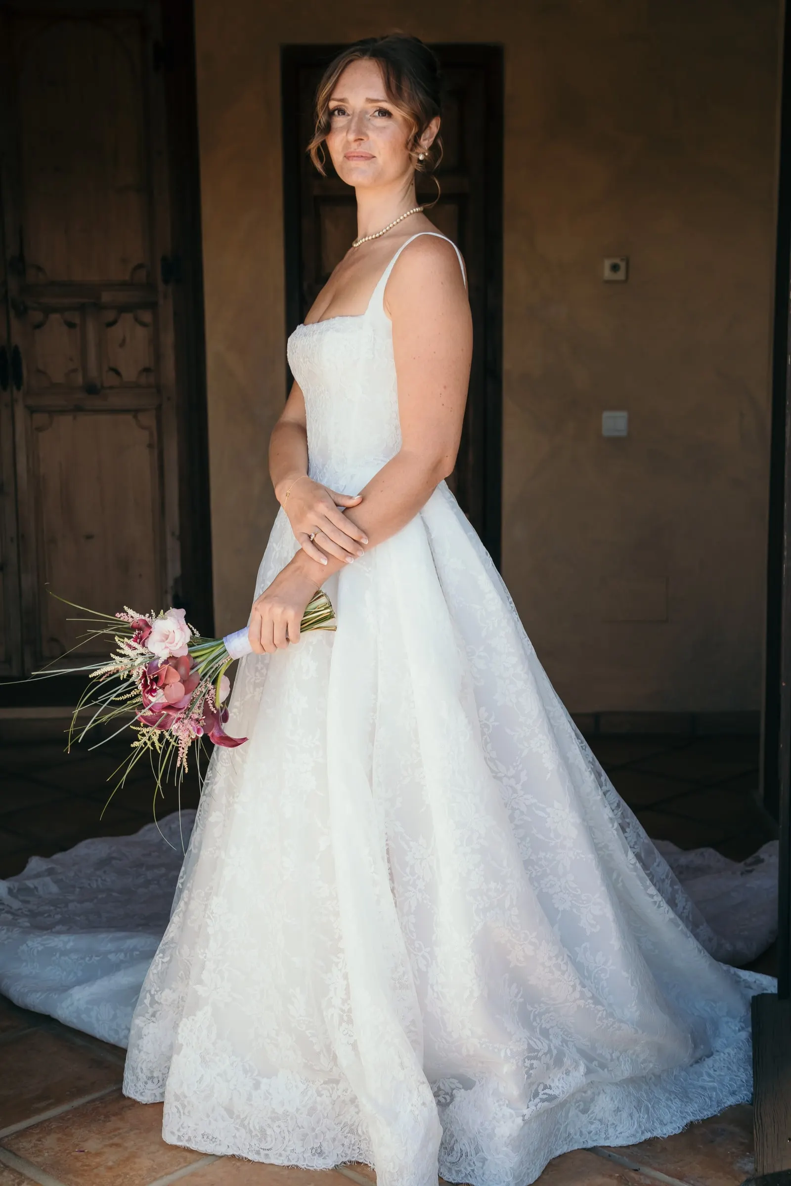 The bride looking over her shoulder in a dim room, bouquet held low, Hacienda San José, Mijas