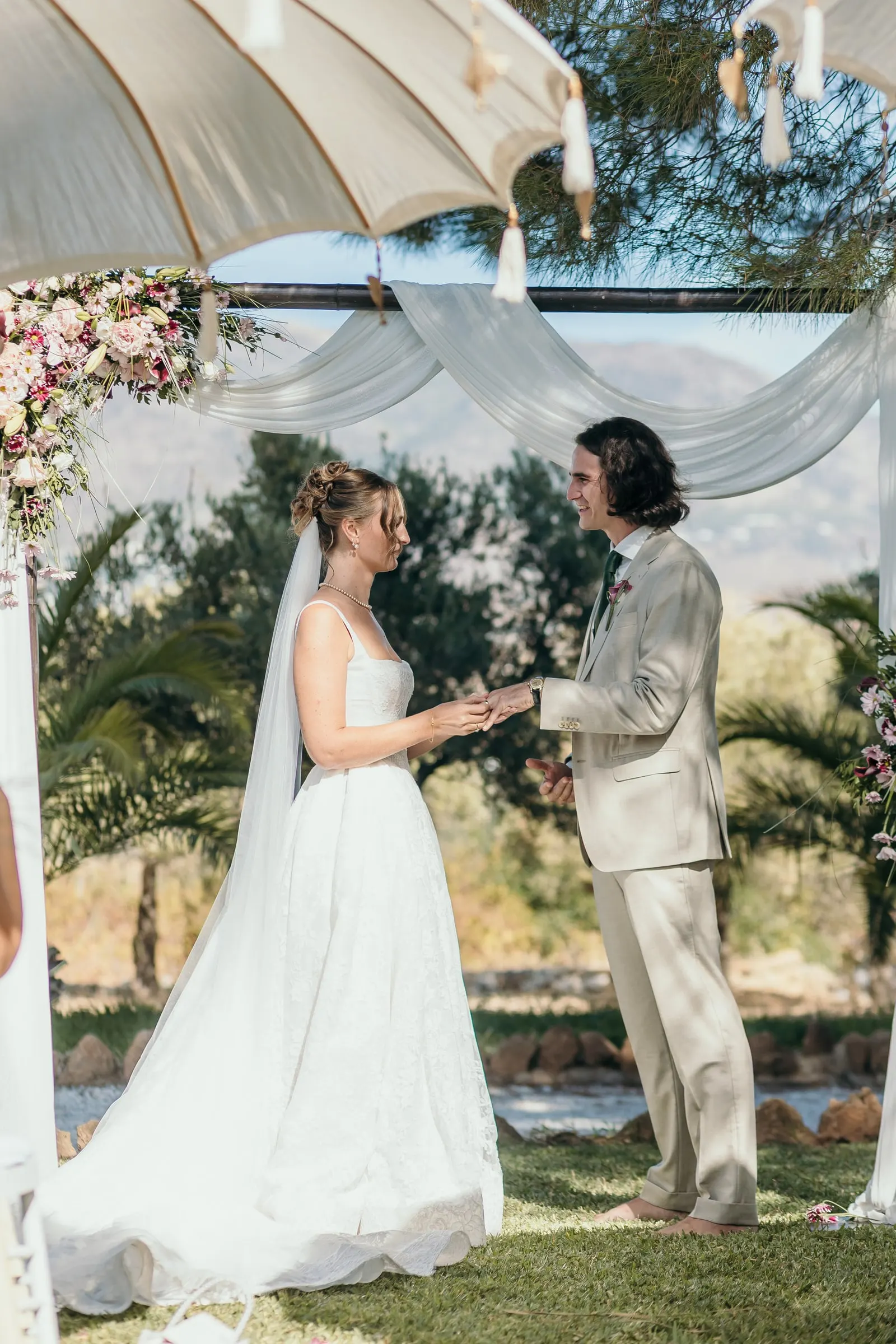 Bride and groom exchanging rings under the draped canopy and parasols, Hacienda San José, Mijas