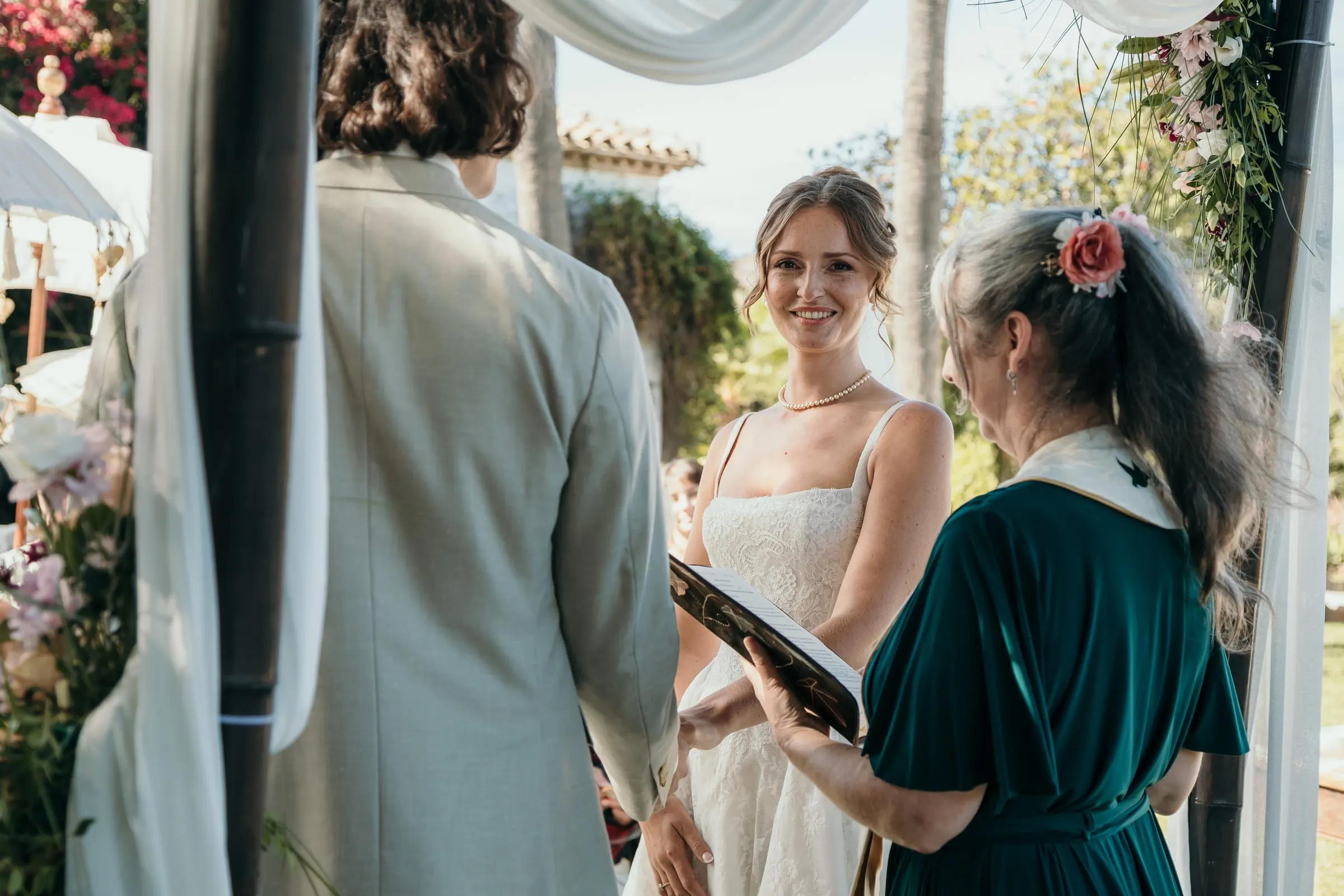 The bride smiling as the officiant in green reads beside her, Hacienda San José, Mijas