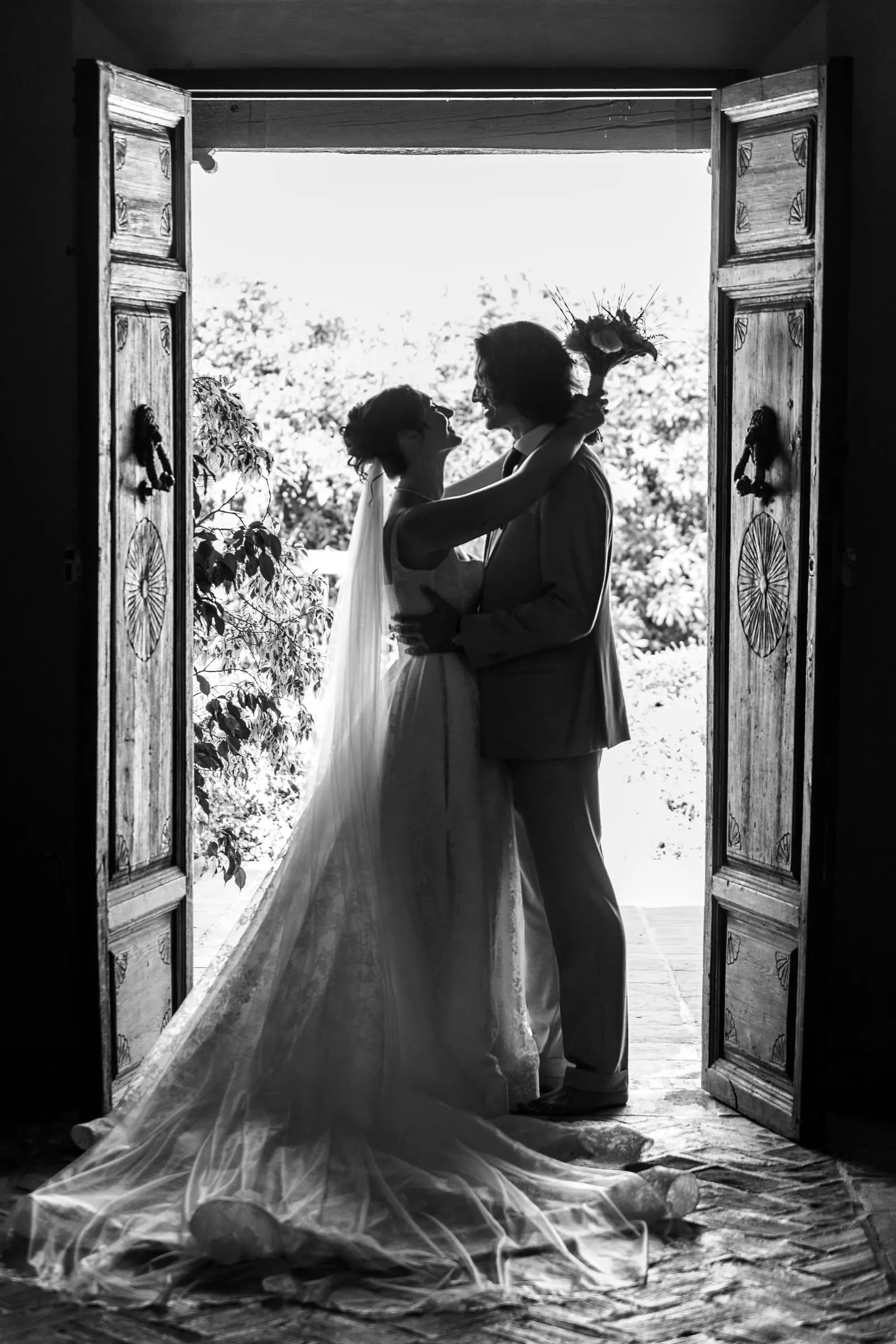 Black and white silhouette of the couple embracing in an open double doorway, Hacienda San José, Mijas