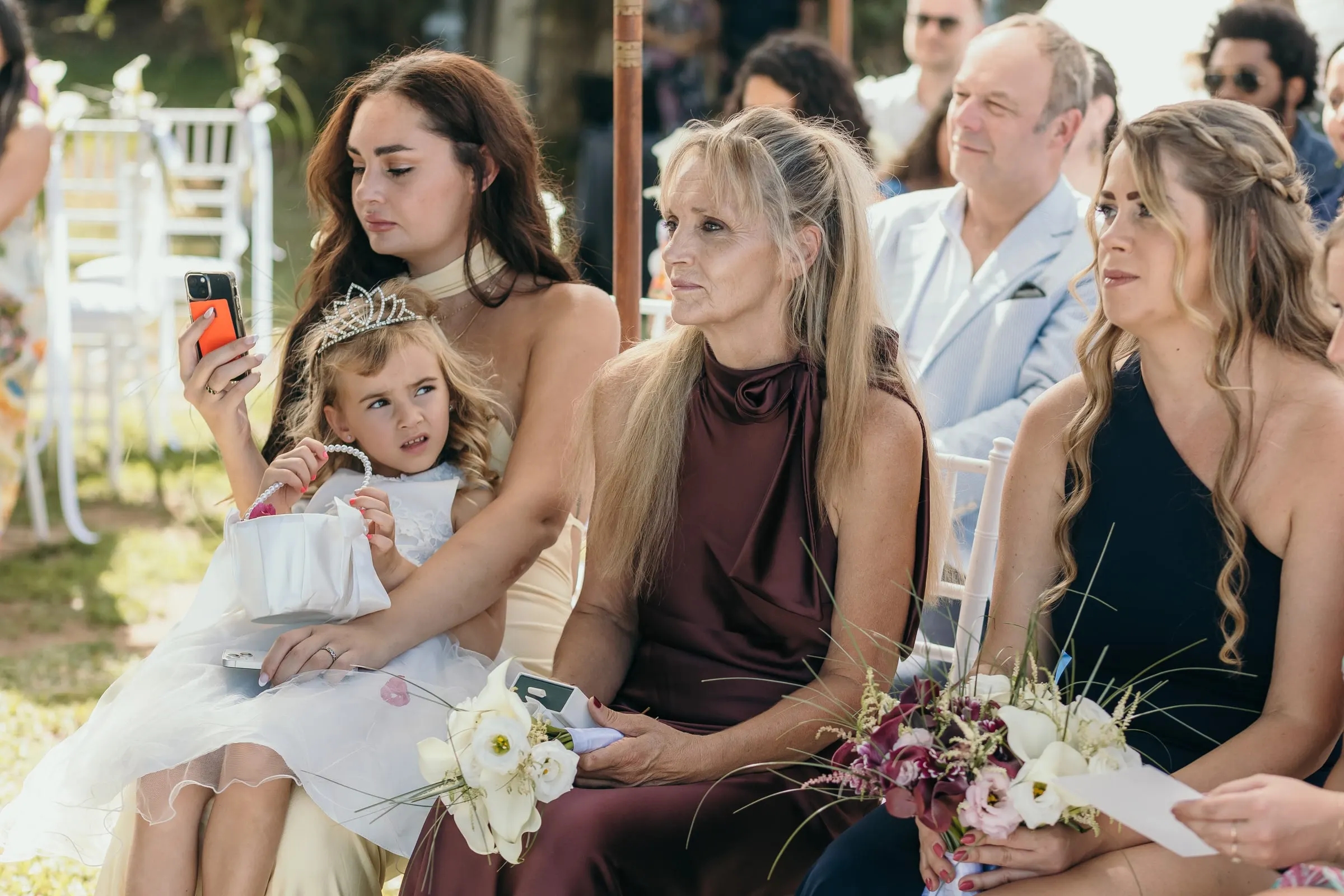 Guests watching the ceremony, one filming with the flower girl on her lap, Hacienda San José, Mijas