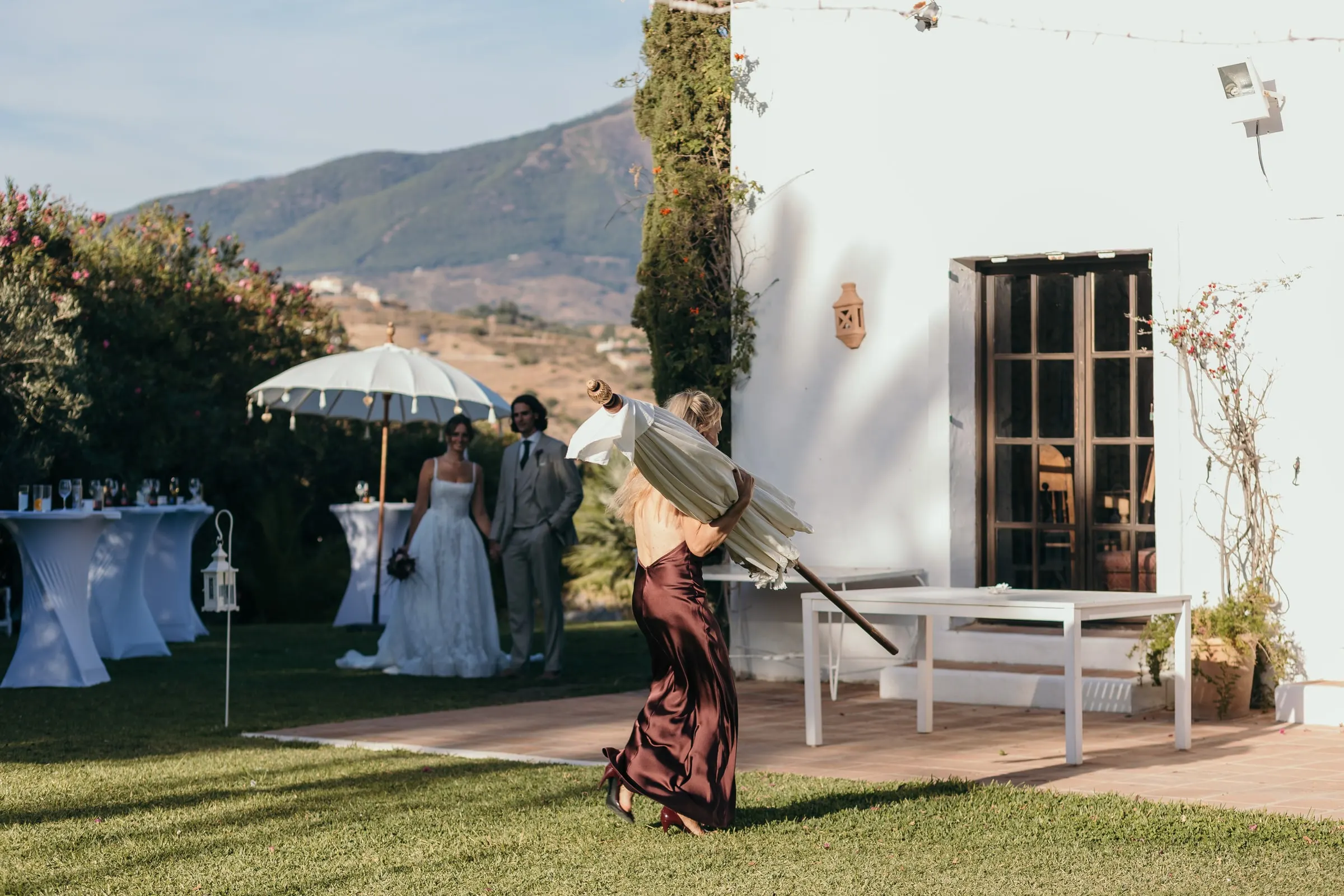The couple by the white farmhouse as a guest with a parasol crosses the lawn, Hacienda San José, Mijas