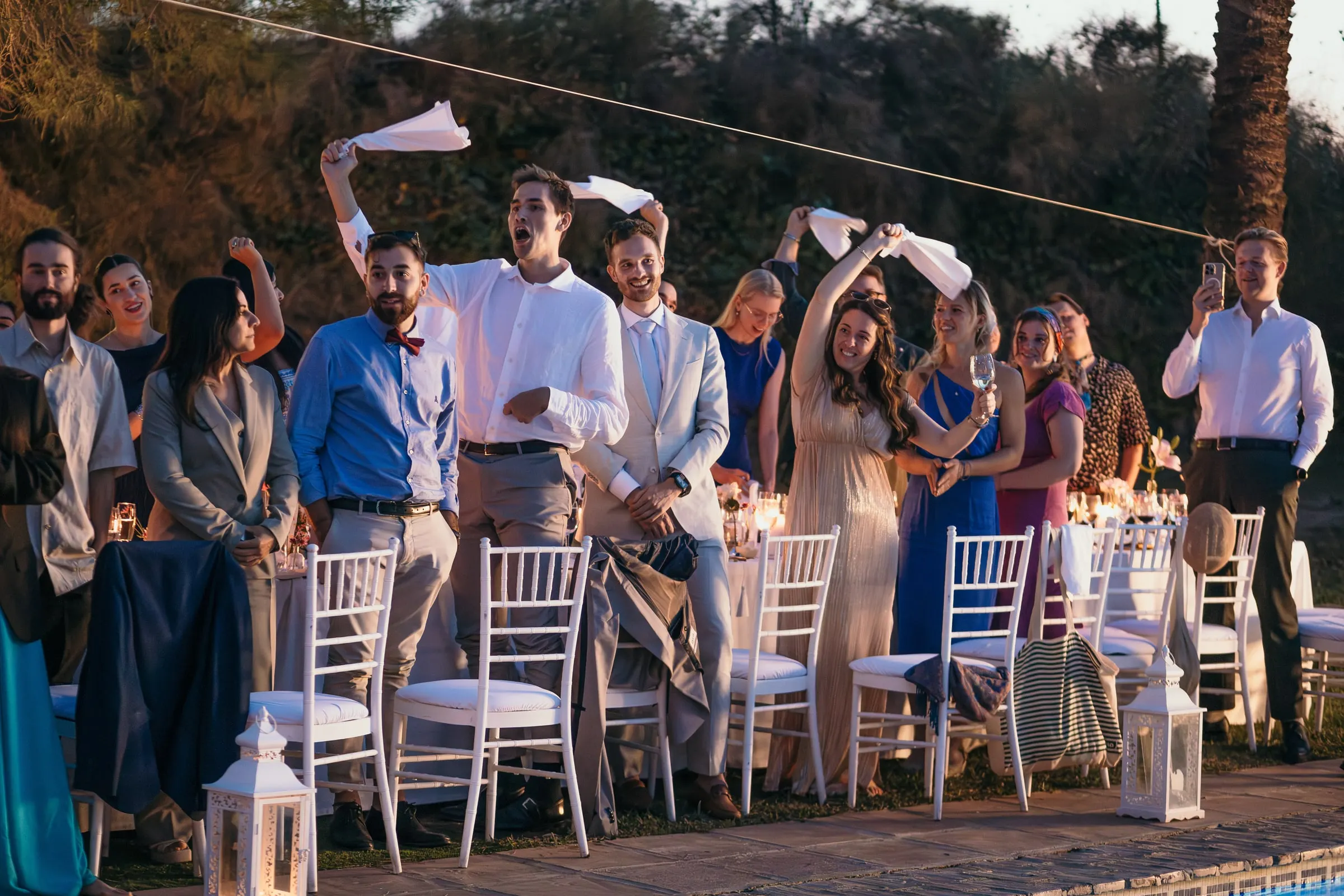 Guests standing by the dinner tables waving white napkins in the air at dusk at Hacienda San José, Mijas