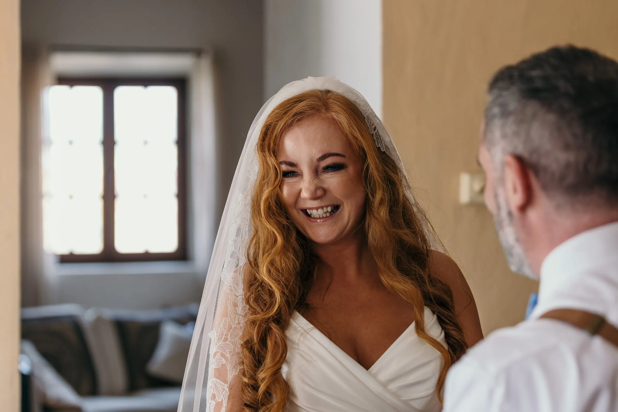 Bride laughing as she is seen in her dress and veil for the first time at Hacienda San José