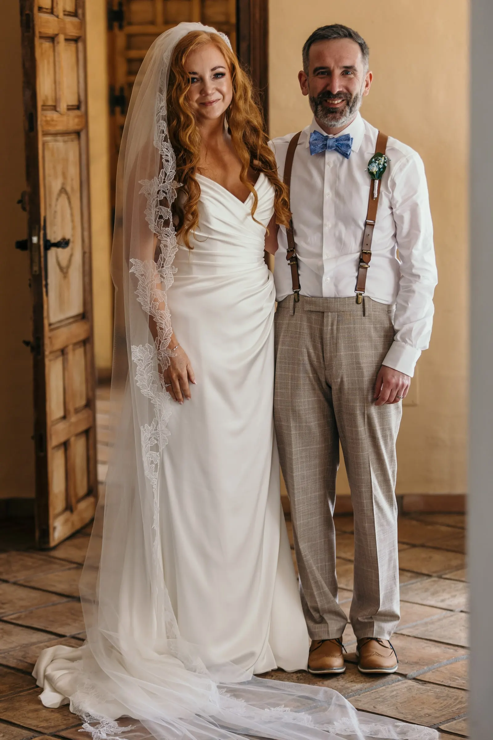 Bride with the man who walks her down the aisle, side by side by a wooden door at Hacienda San José