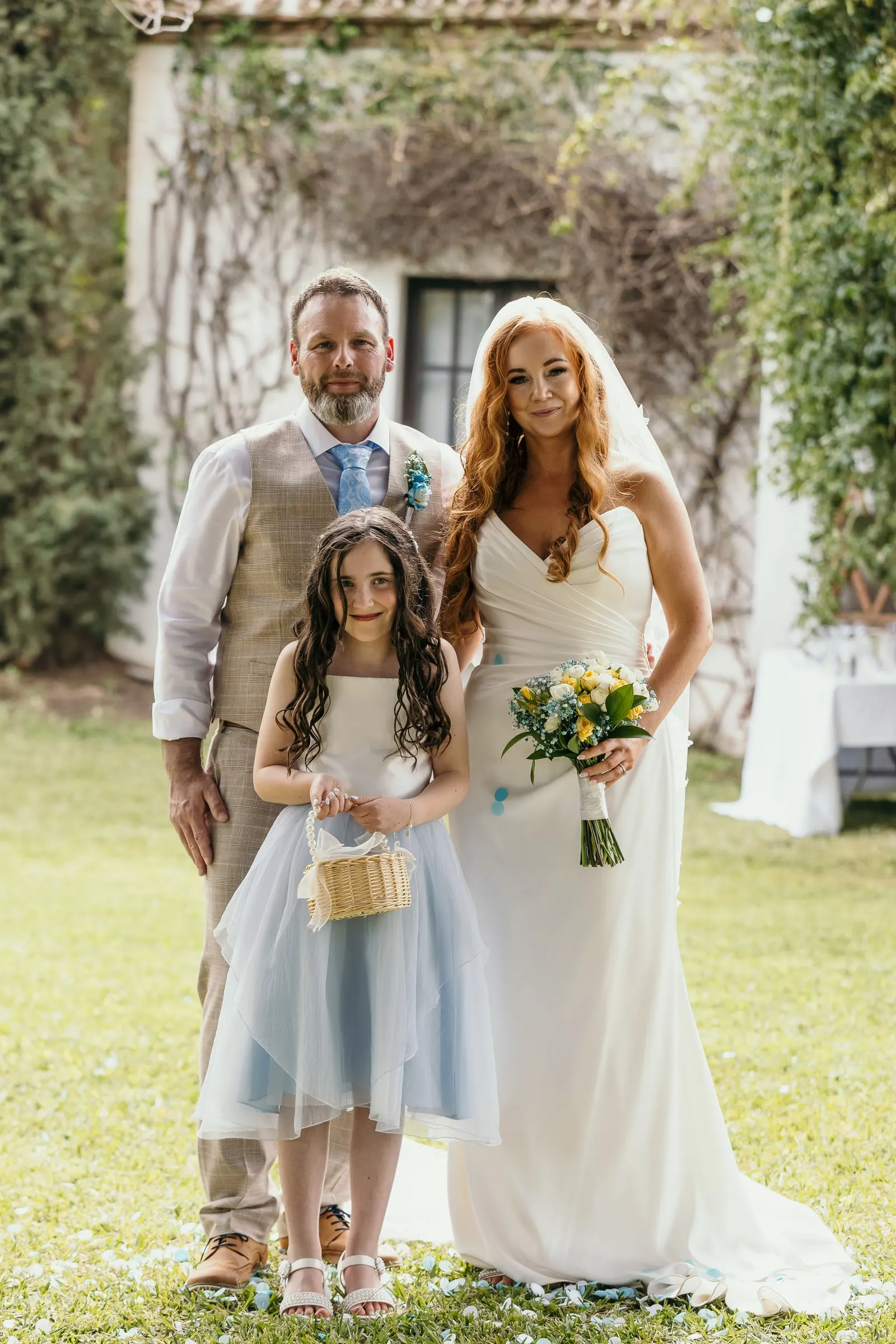 Bride, groom and the flower girl in pale blue posing together on the grass in Mijas