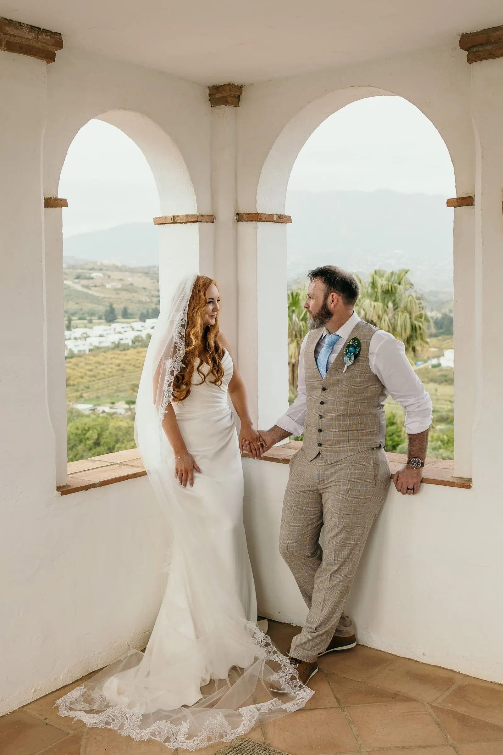 Bride and groom in the white arched tower of Hacienda San José with the valley behind