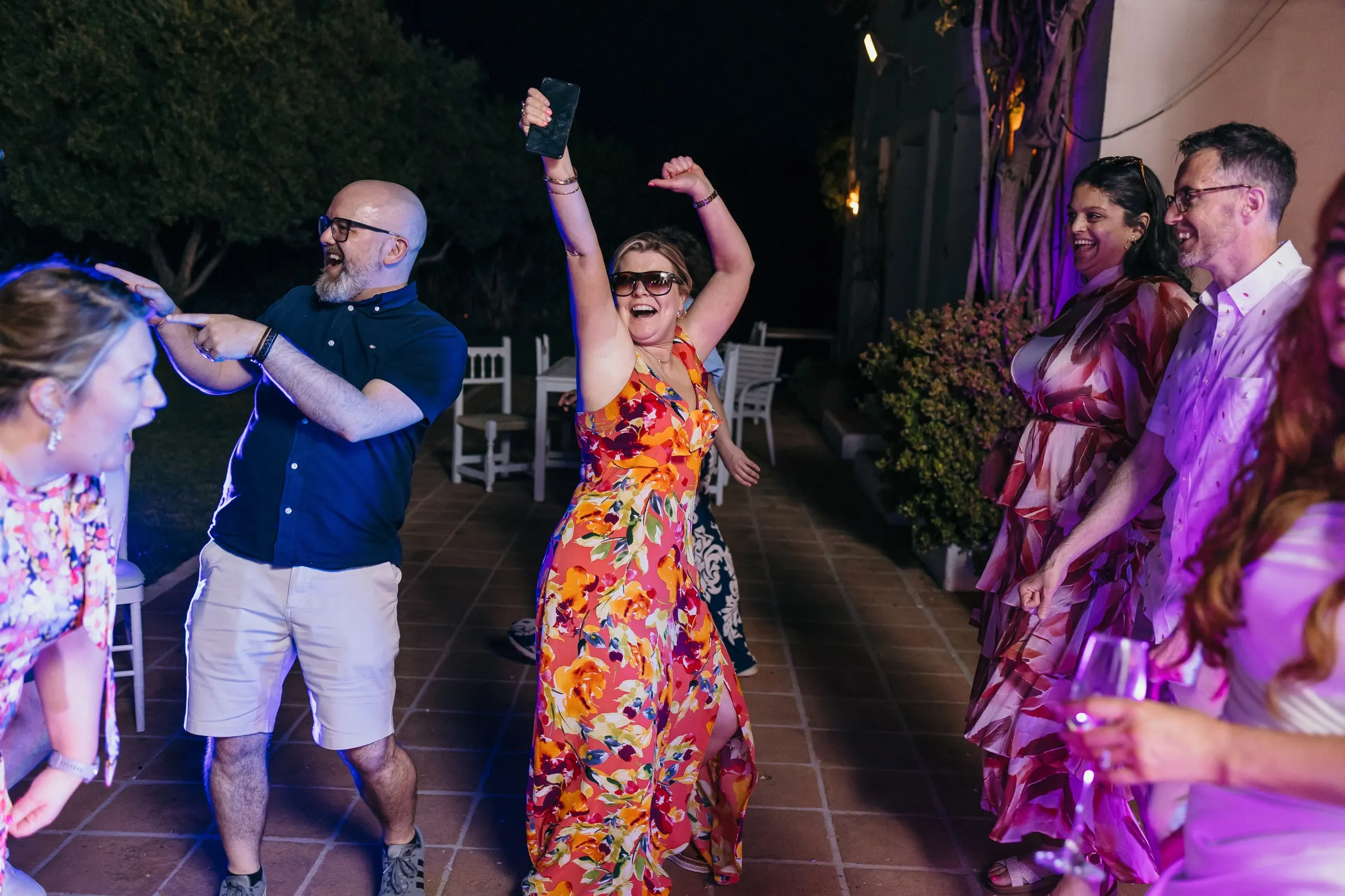 Guests dancing in sunglasses and summer dresses on the terrace at night, Mijas