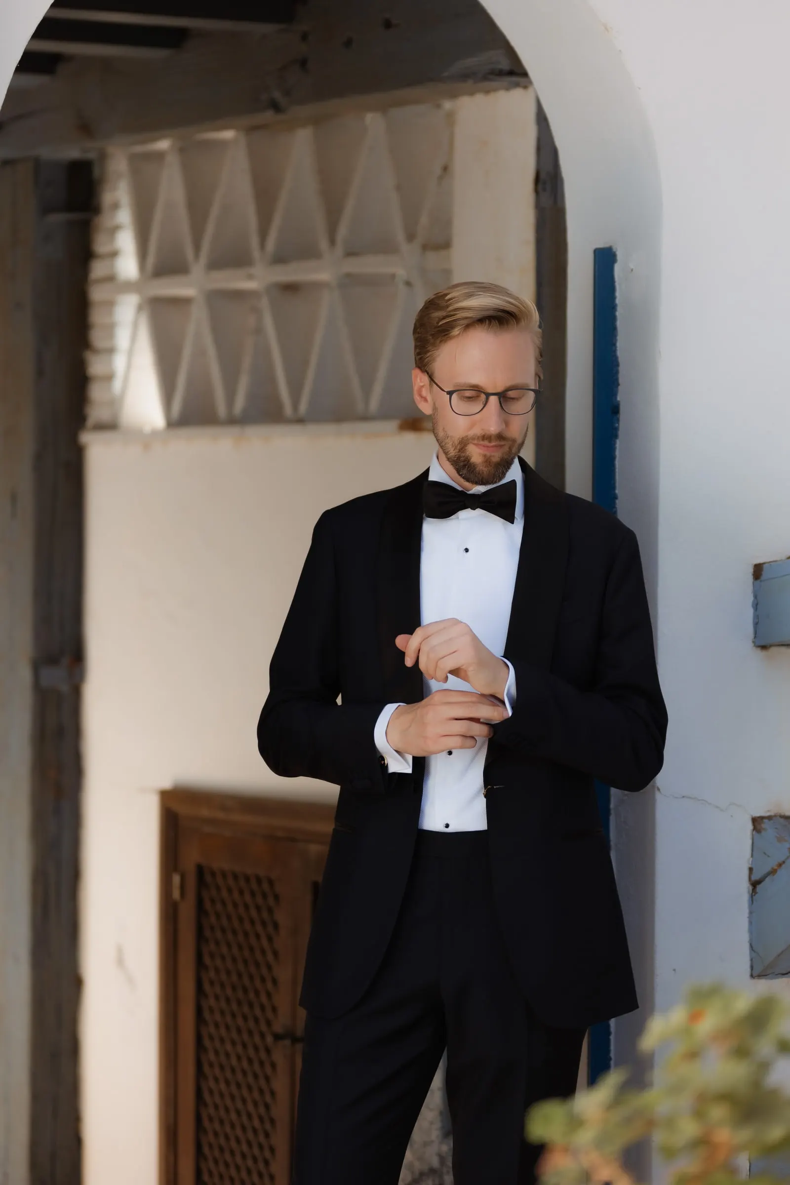Groom fastening a cufflink under a whitewashed arch of the Ronda finca
