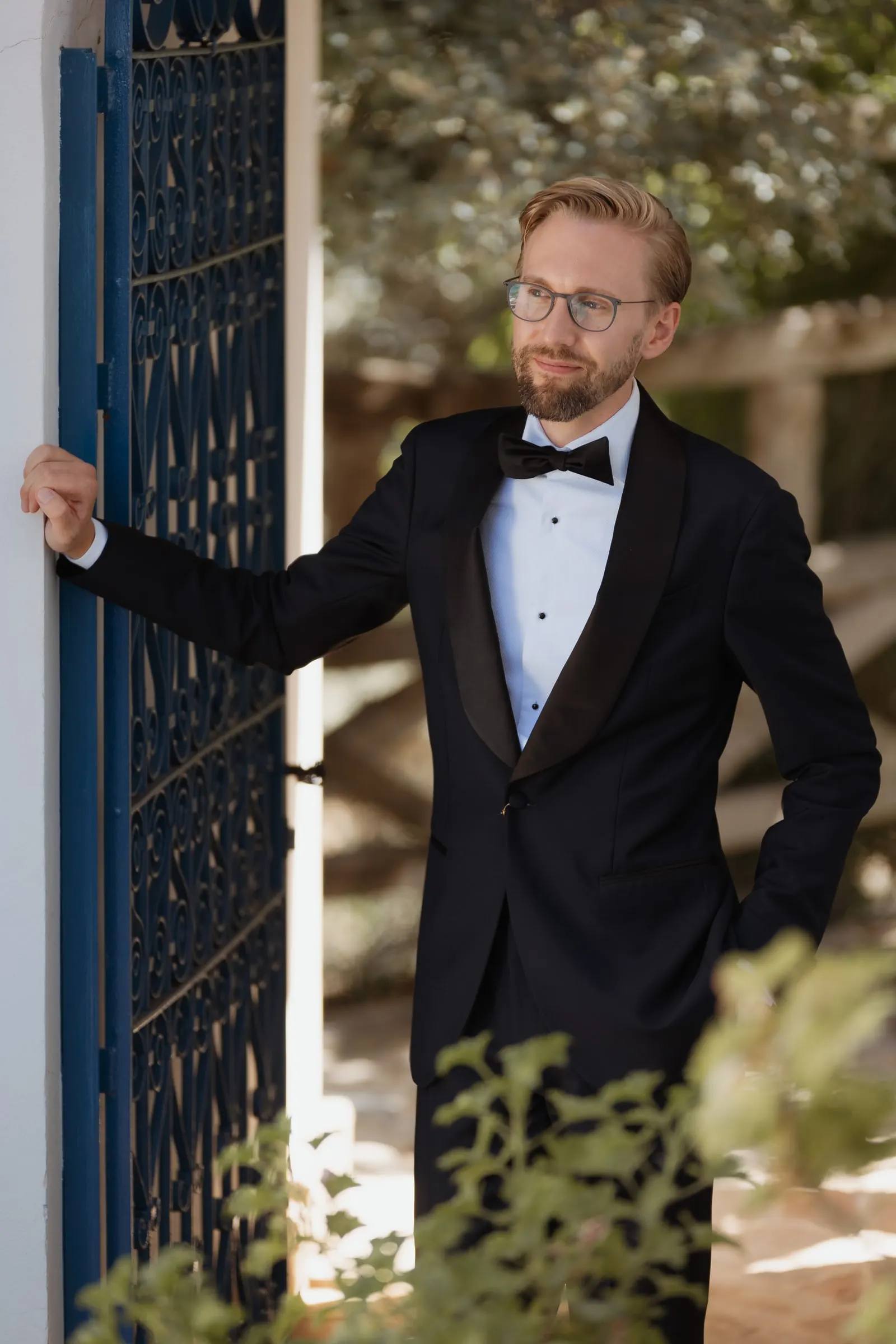 Groom leaning on the blue gate, ready for his wedding at Los Pilares de Ronda