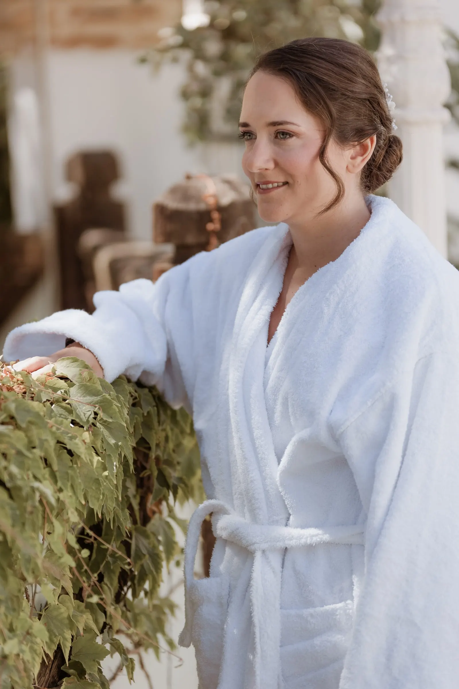 Bride in a white robe smiling by the window at Los Pilares de Ronda