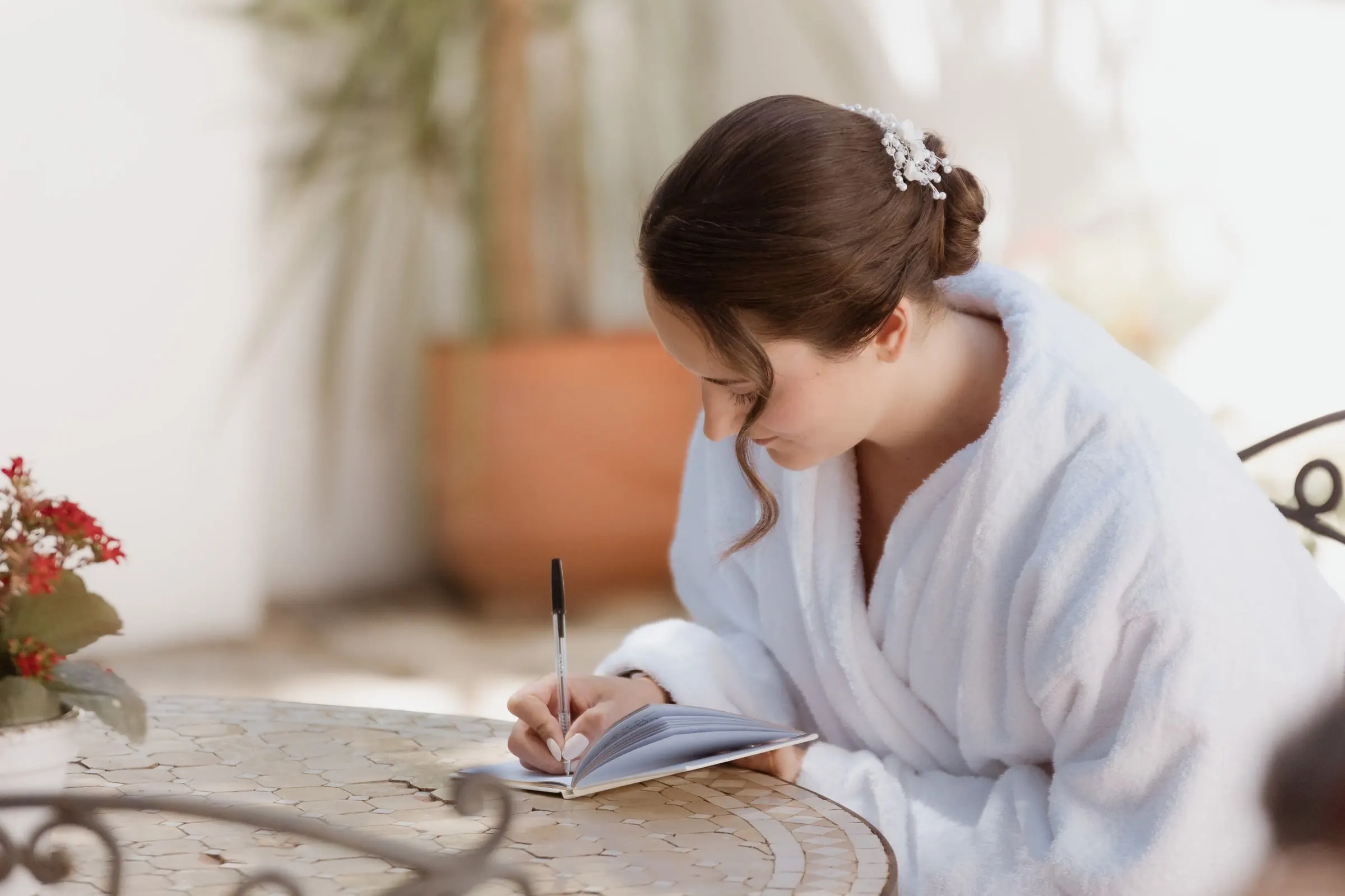 Bride in her robe writing her vows at a garden table