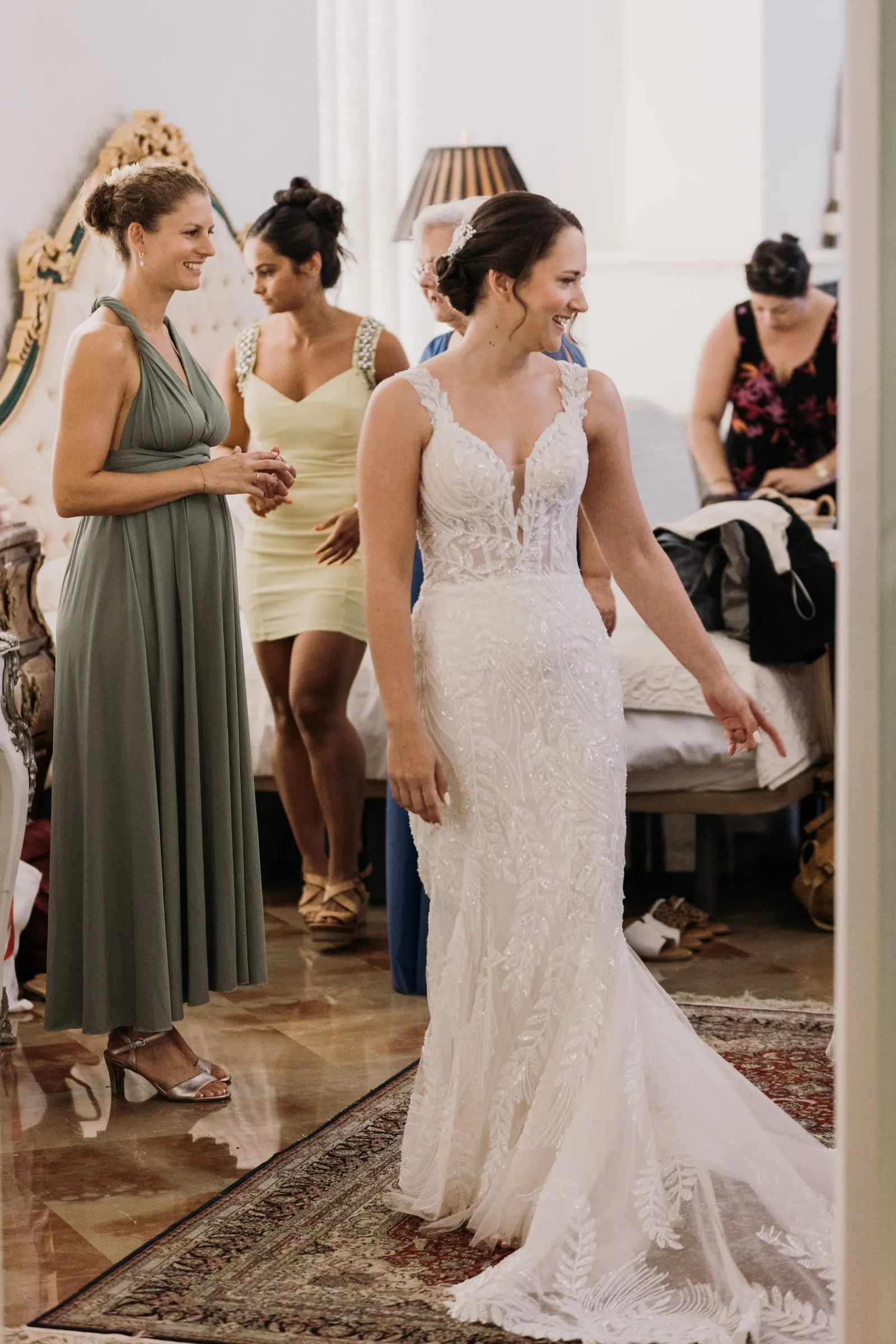 Bride in her lace gown surrounded by bridesmaids in the bridal room in Ronda