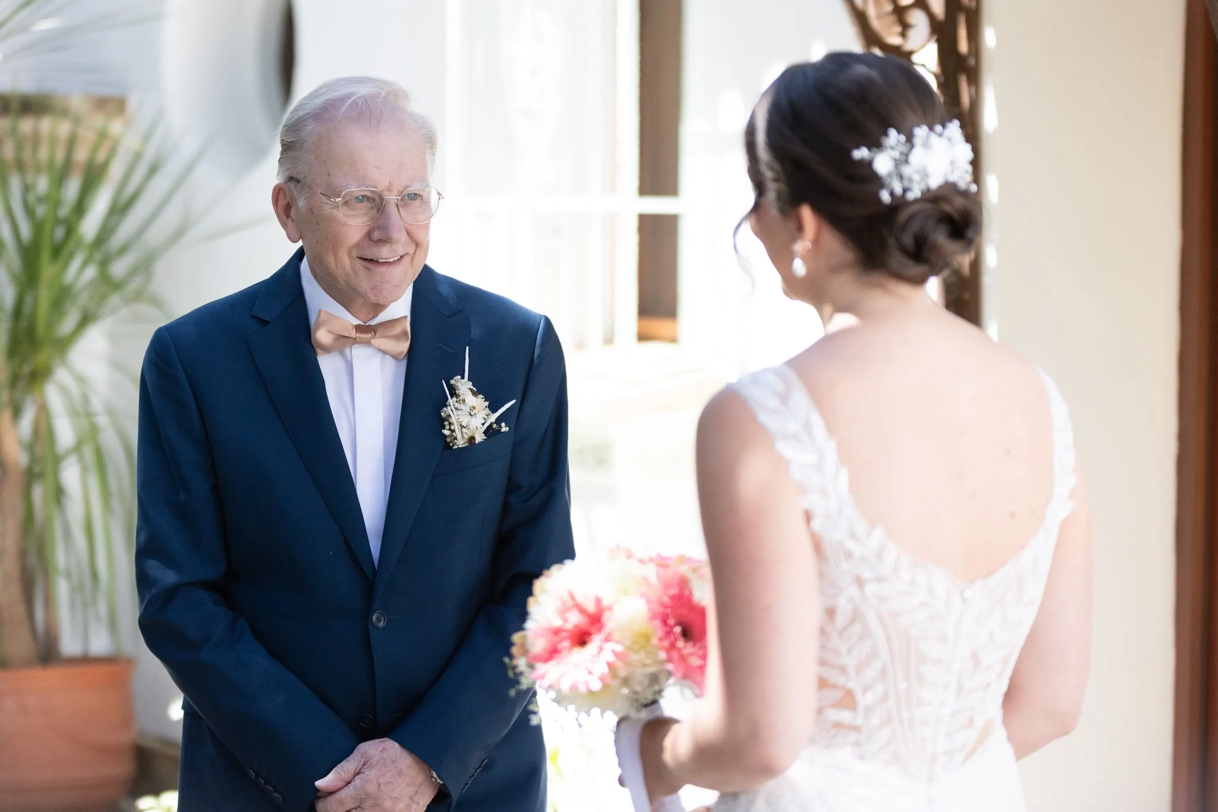 Older relative in a blue suit seeing the bride in her dress for the first time
