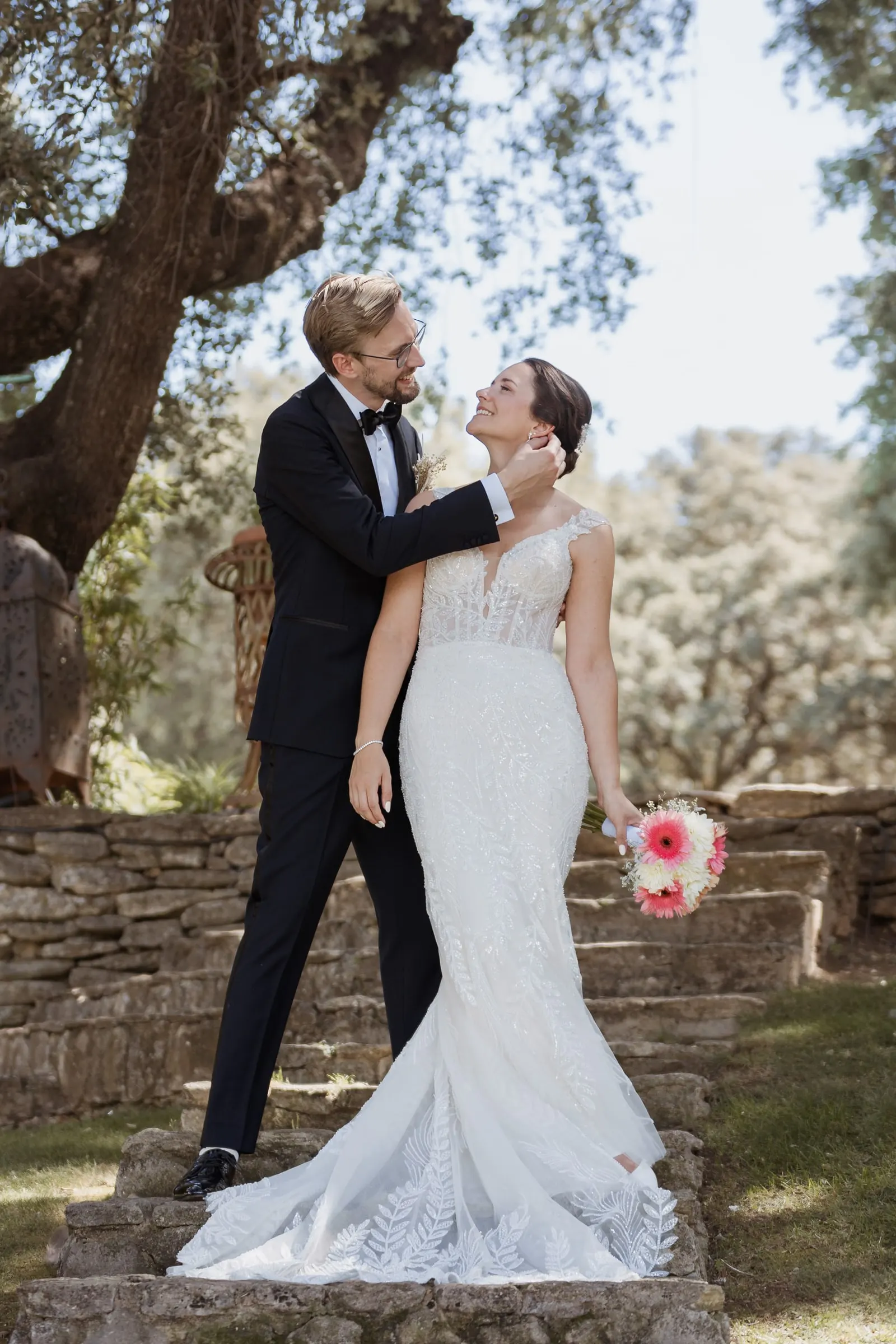 Groom playfully holding the bride's face under an old oak in Ronda