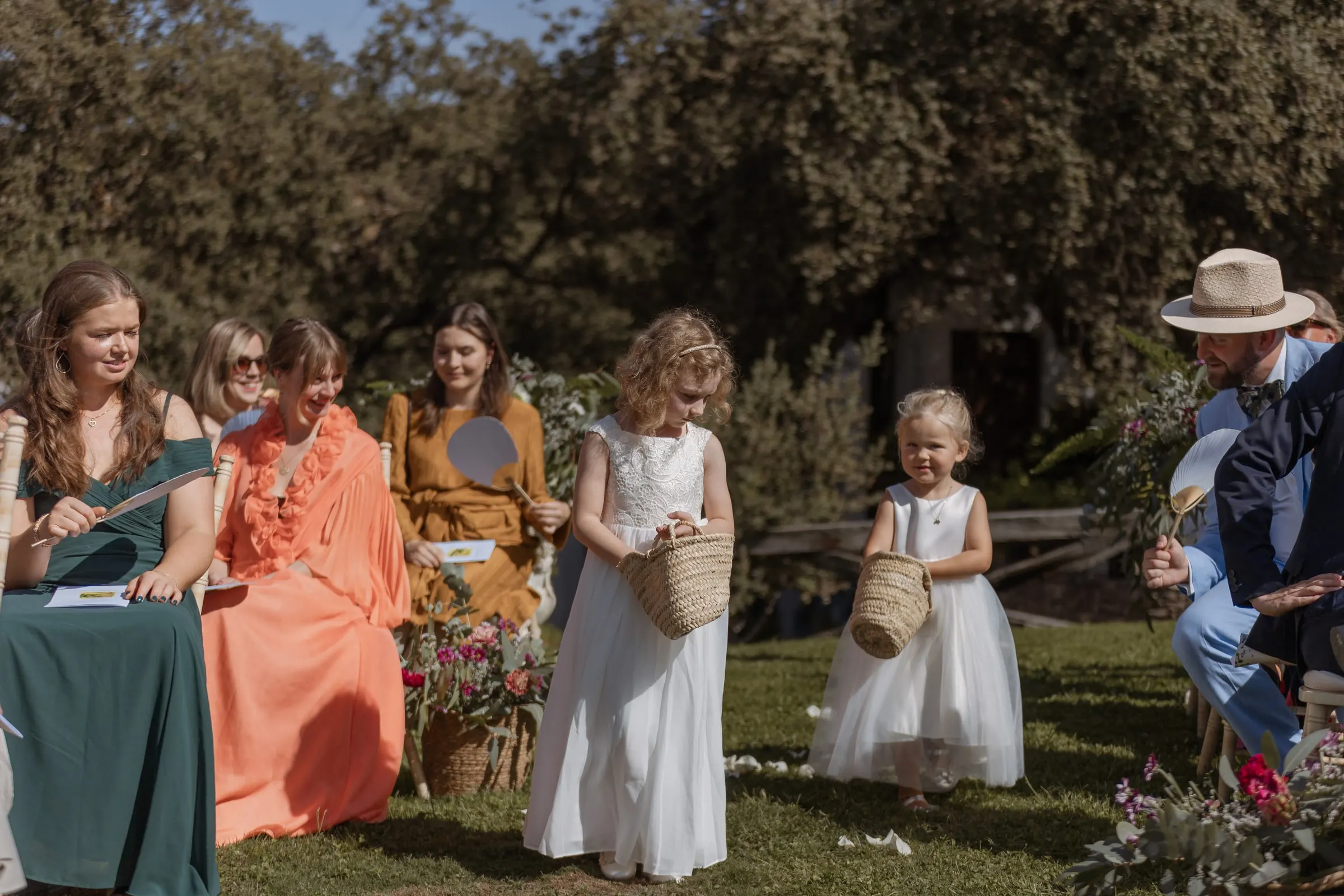 Flower girls with baskets walking down the aisle in the garden