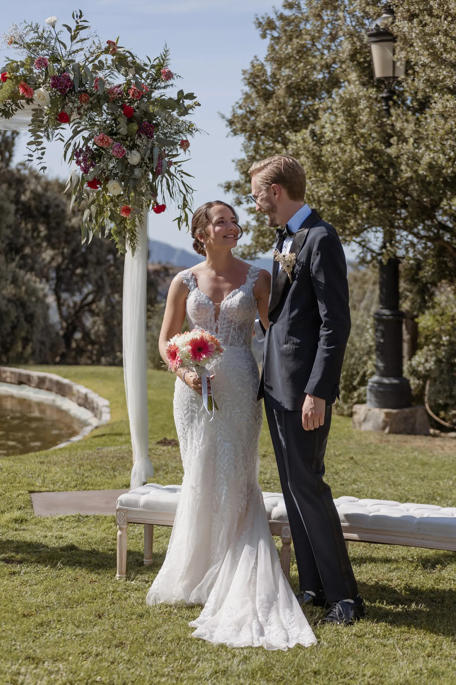 Bride and groom laughing under the floral arch at their Ronda ceremony