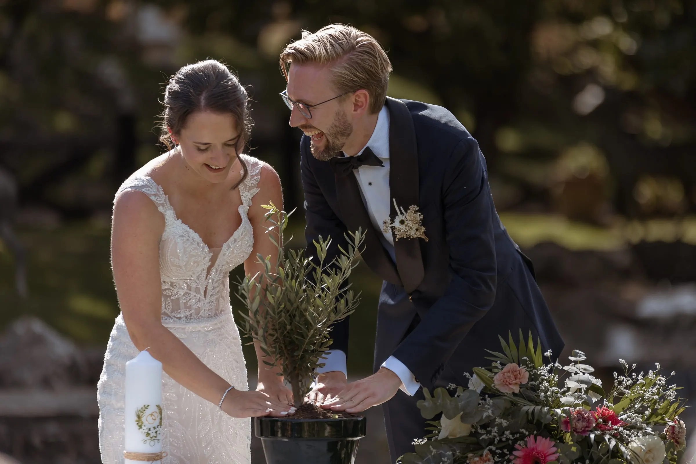 Couple planting a small tree together during the outdoor ceremony