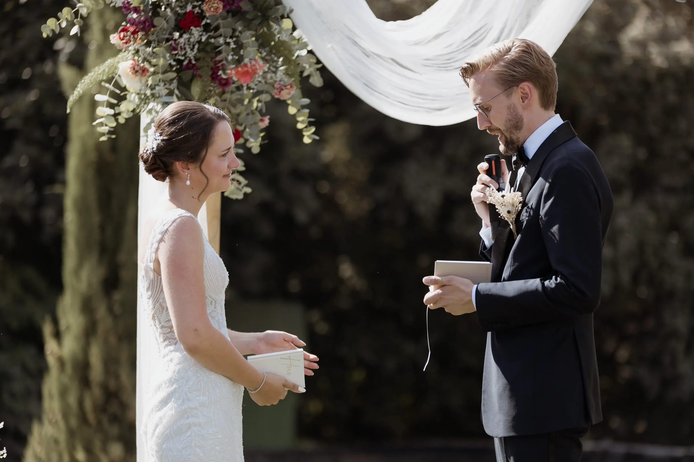 Groom reading his vows to the bride under the arch