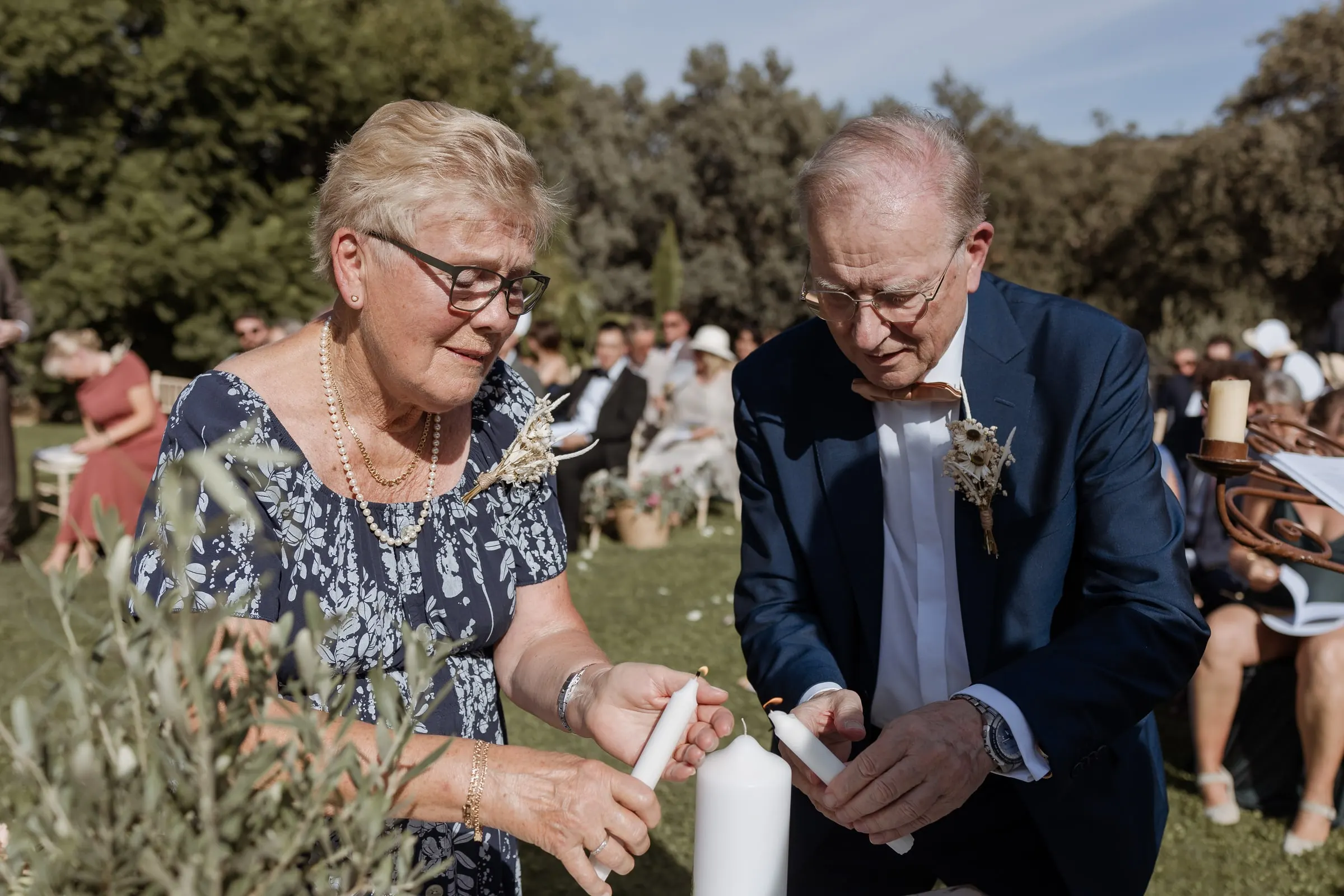Older couple lighting a candle during the ceremony in the garden