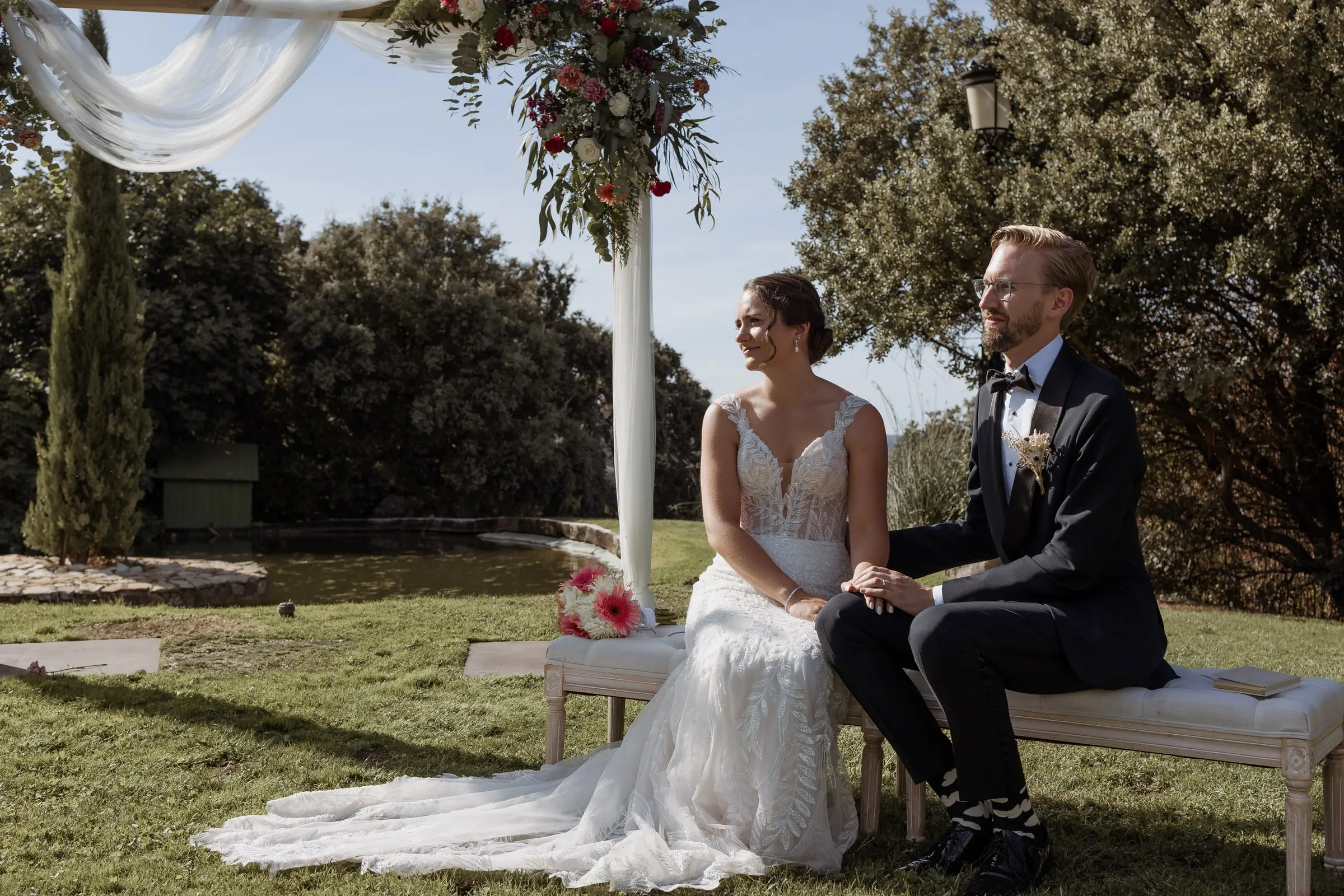 Bride and groom seated on a bench under the arch during the ceremony in Ronda