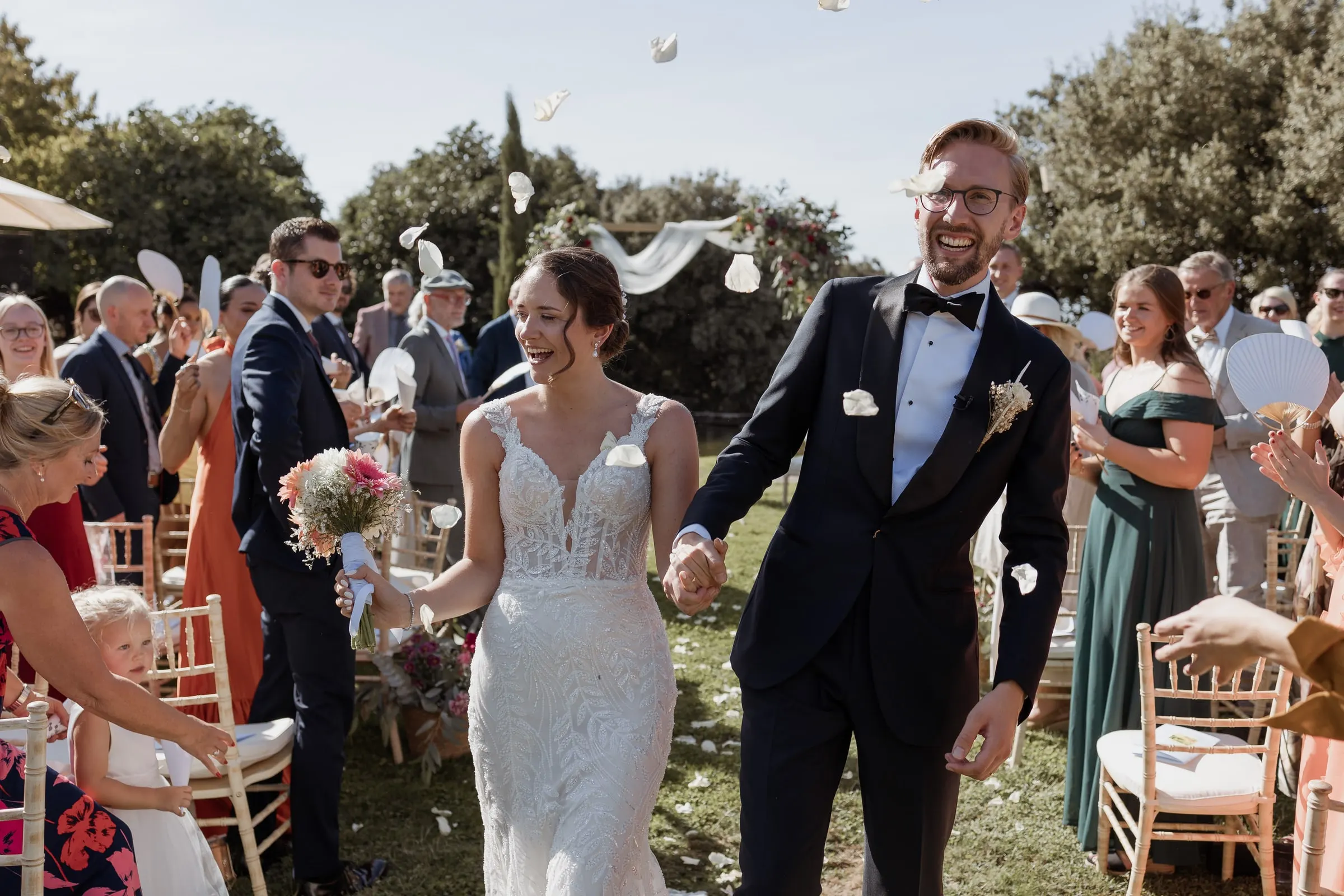 Newlyweds walking back down the aisle as guests throw petals