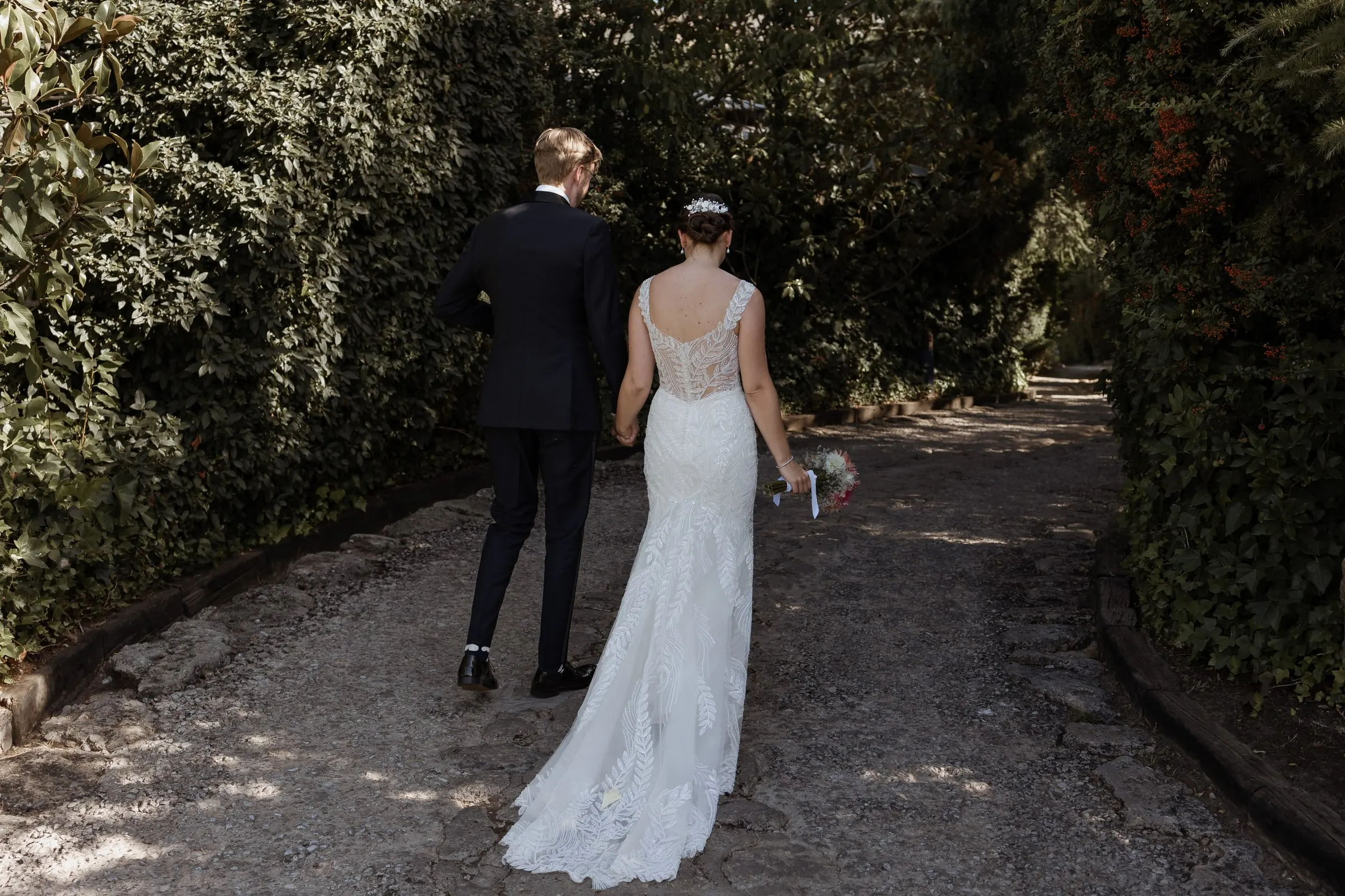 Newlyweds walking away along a shaded gravel path