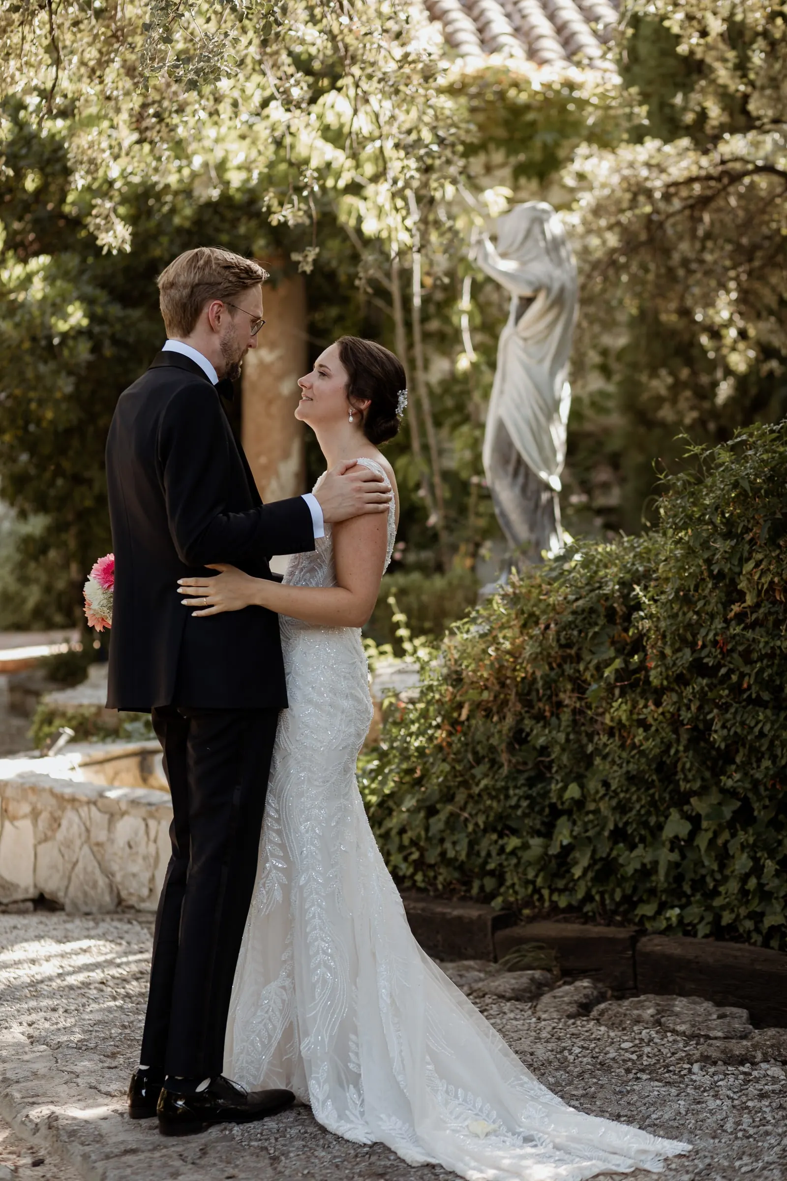 Couple embracing beside a white statue in the garden of the Ronda finca