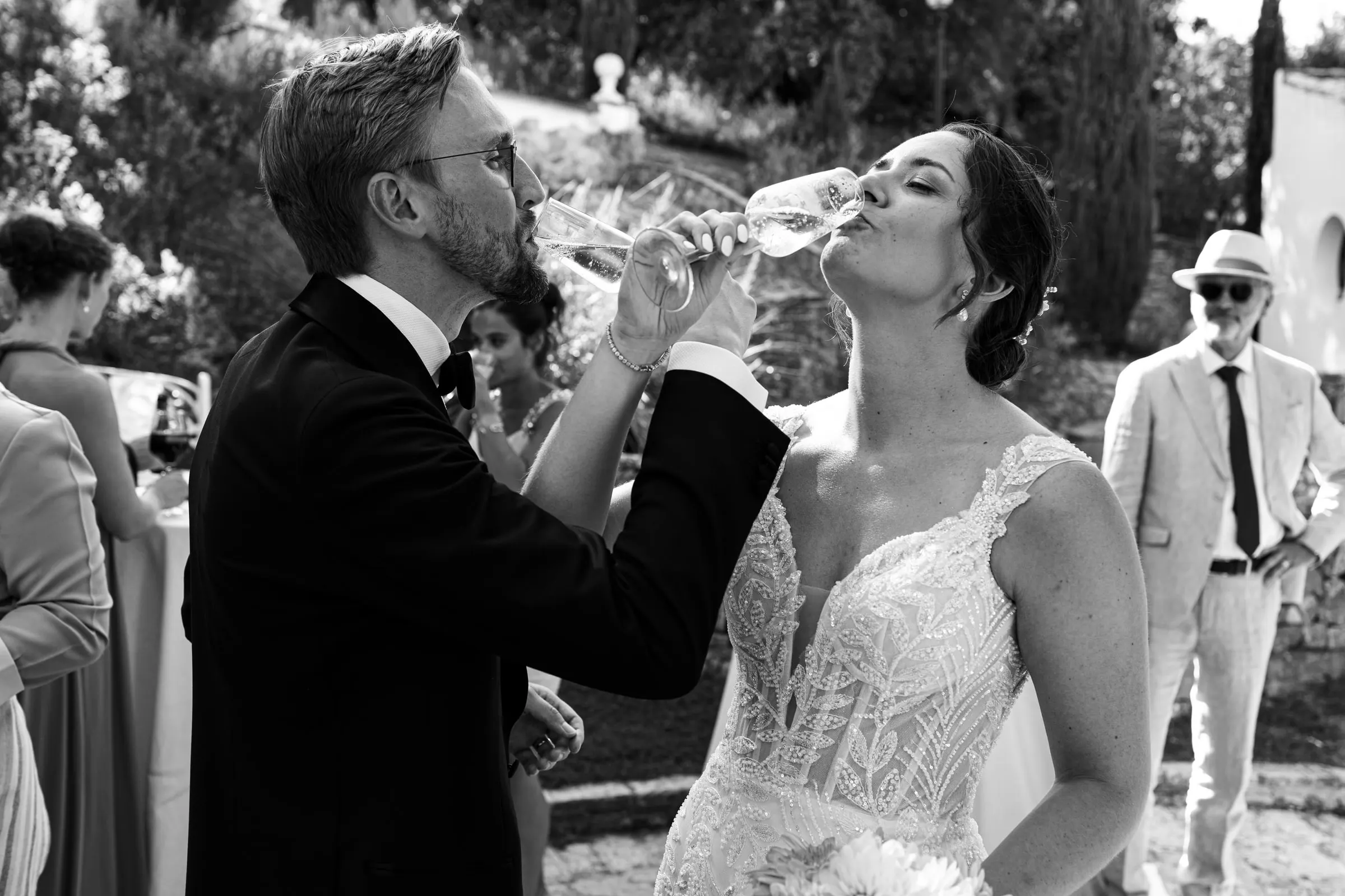 Black and white photo of the bride and groom drinking champagne together