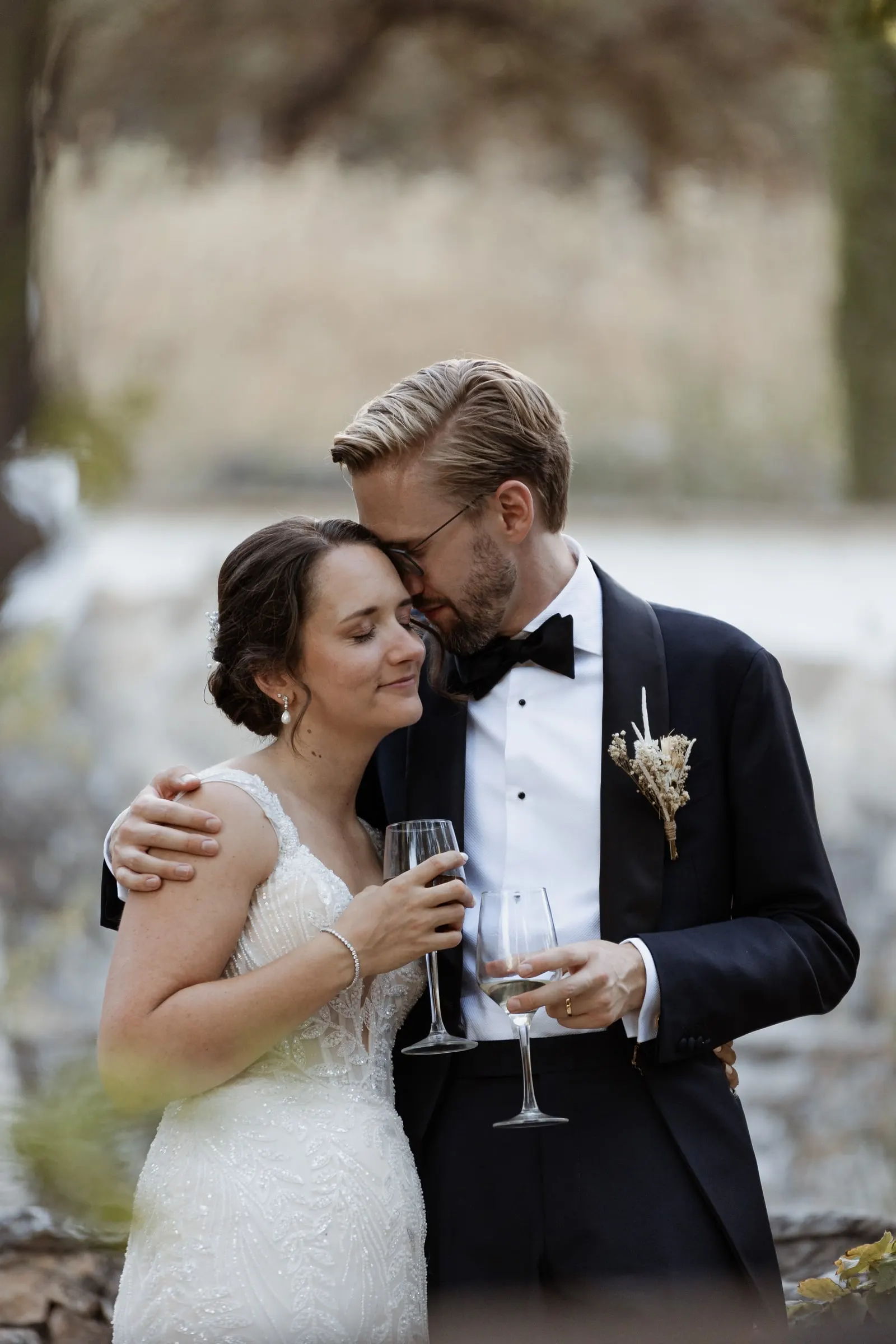 Bride and groom cuddling with glasses of cava after the ceremony