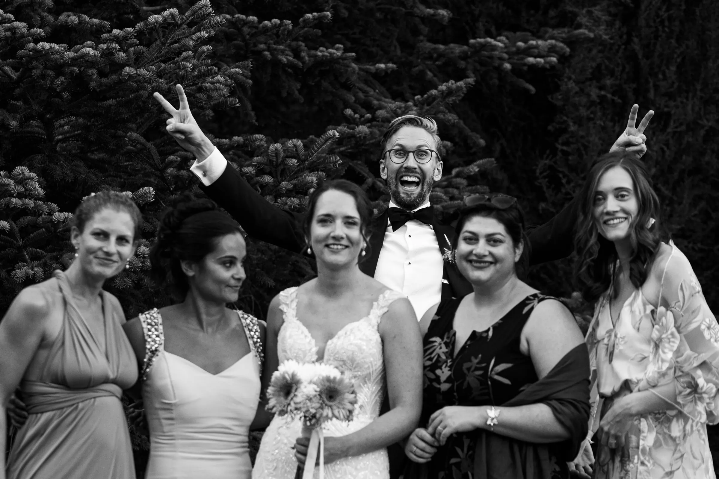 Black and white photo of the bride with her friends as the groom photobombs